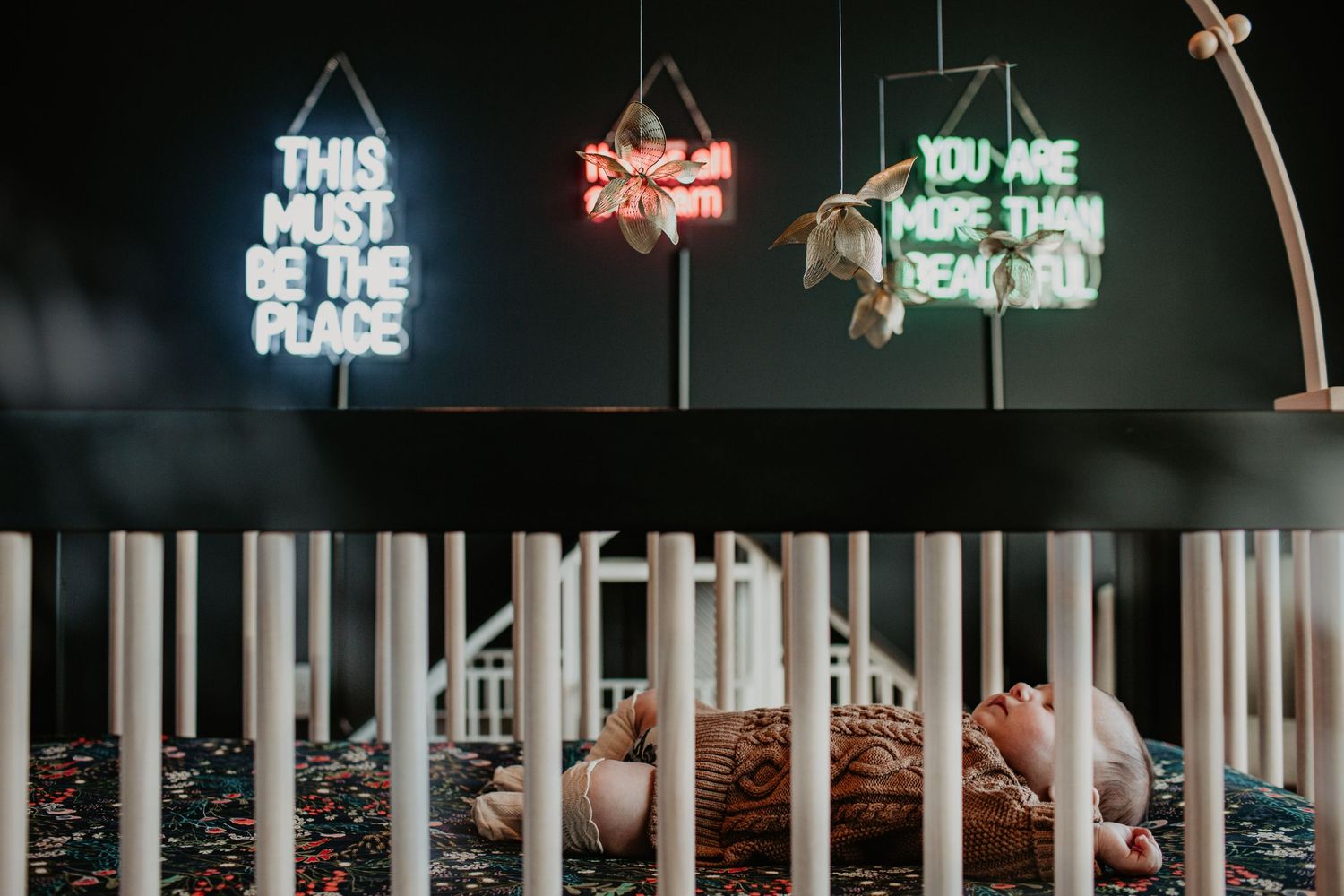 Illuminated neon signs displayed in a dark nursery room with a crib.