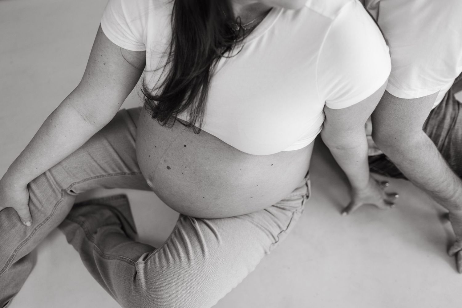 Black and white maternity photo showing a pregnant belly in natural light.