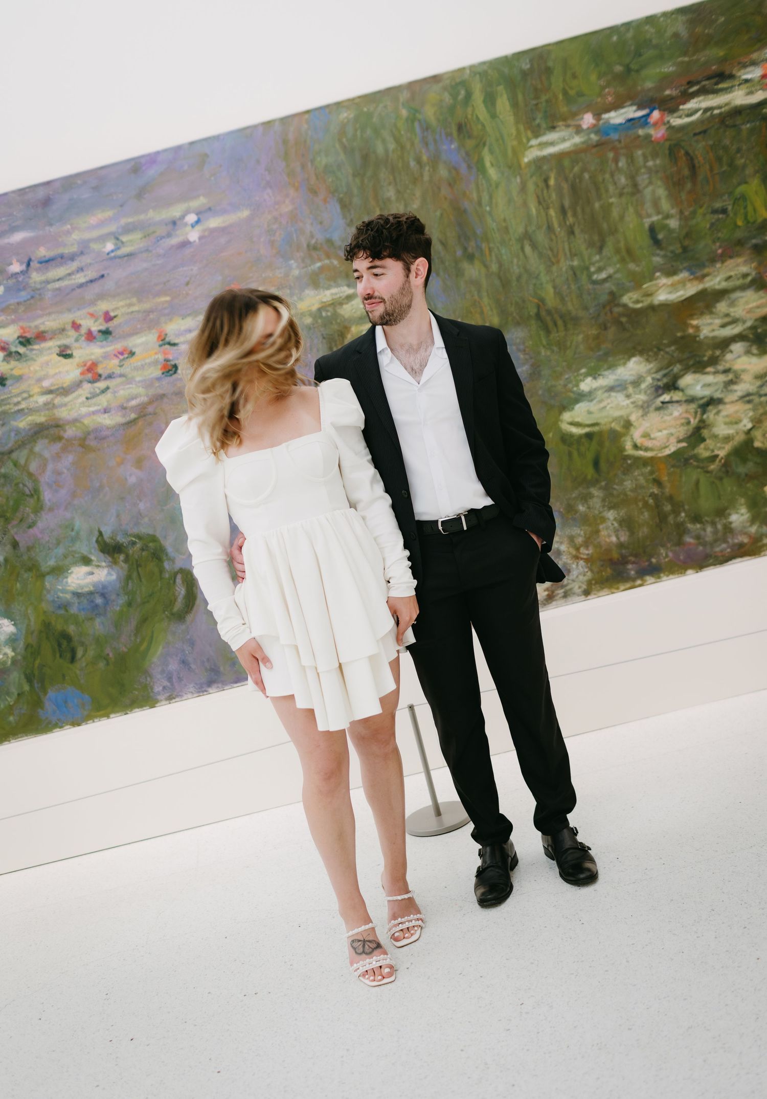 Couple poses in art museum in front of large impressionist painting.