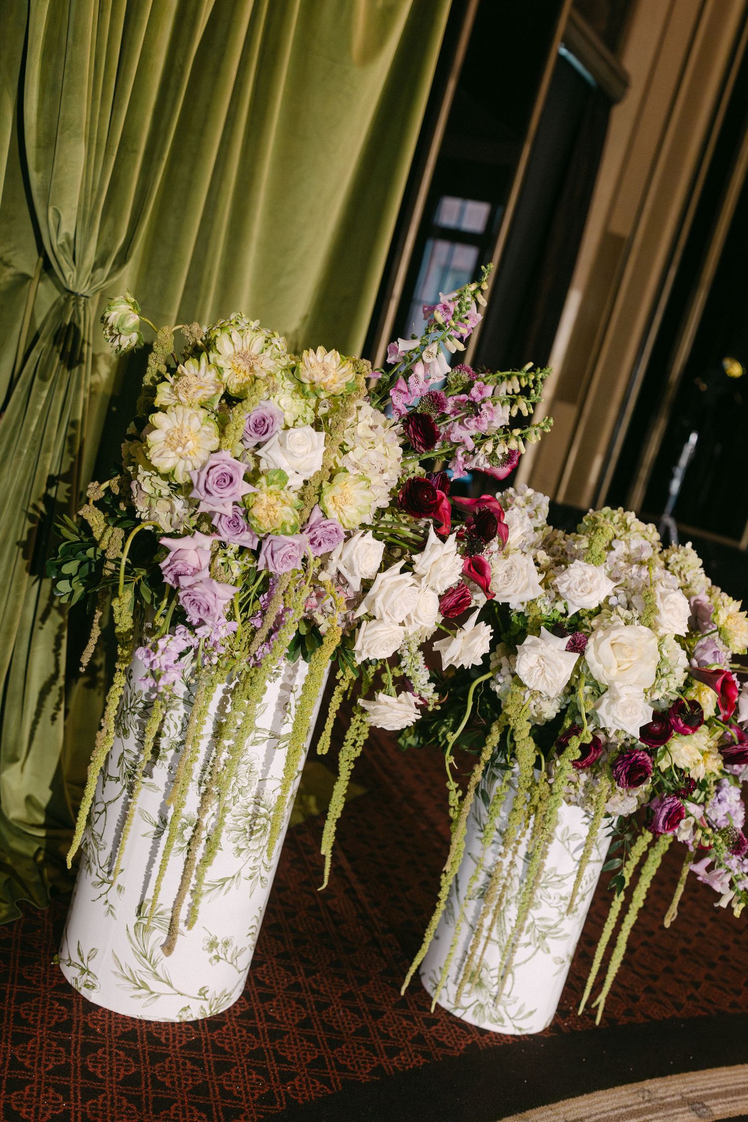 Elegant floral arrangement with pink and white flowers cascading from a mirrored crystal vase on a dark patterned tablecloth.