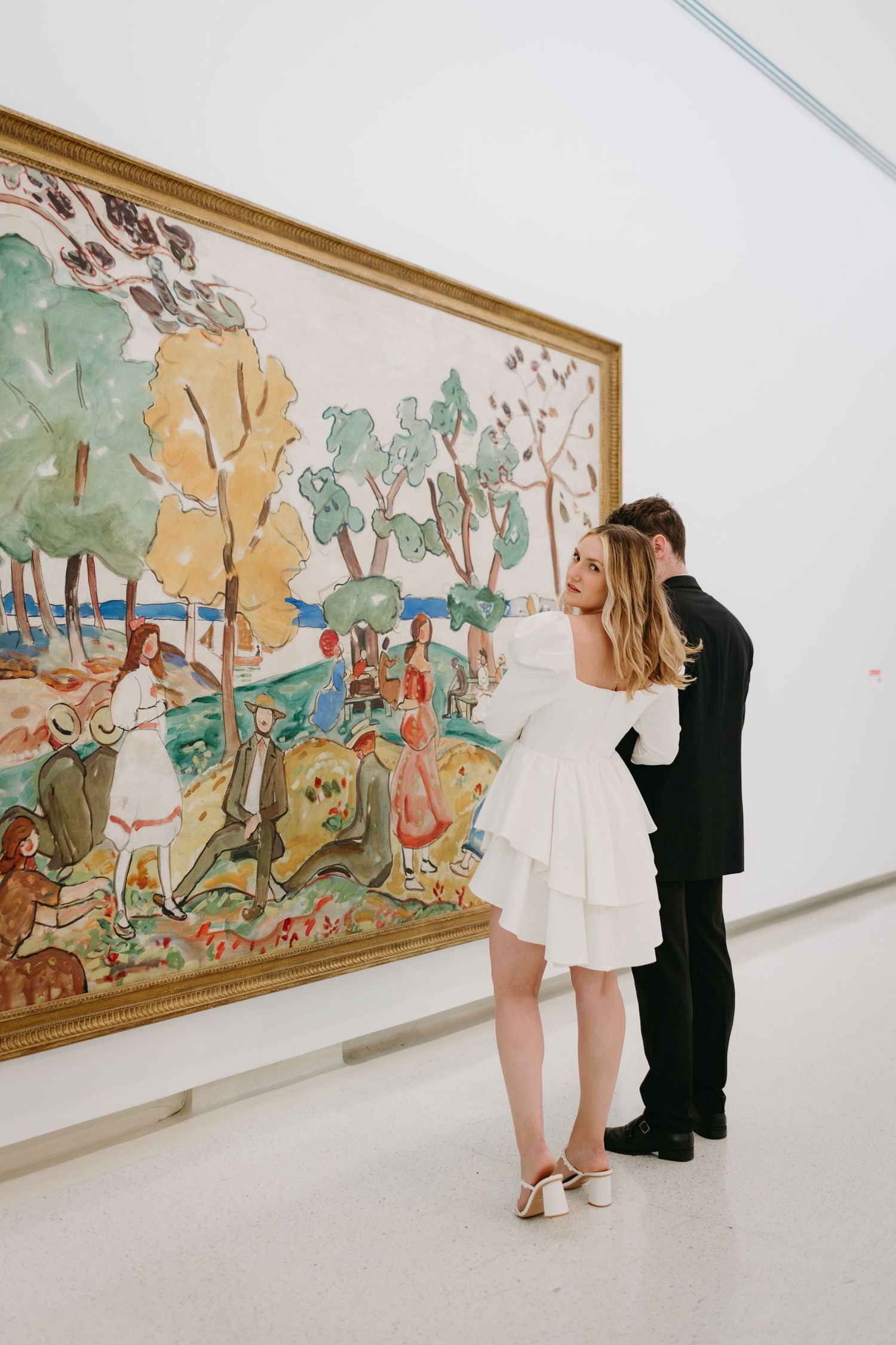 Couple admiring colorful framed artwork in modern gallery setting.