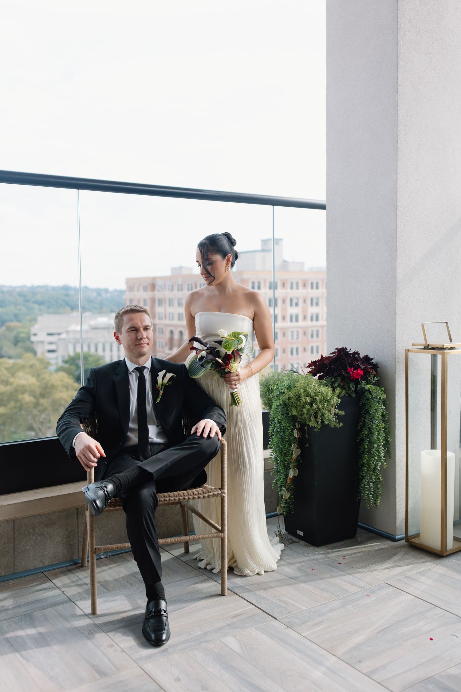 Artistic black and white wedding couple portraits on a modern balcony with city views in the background.