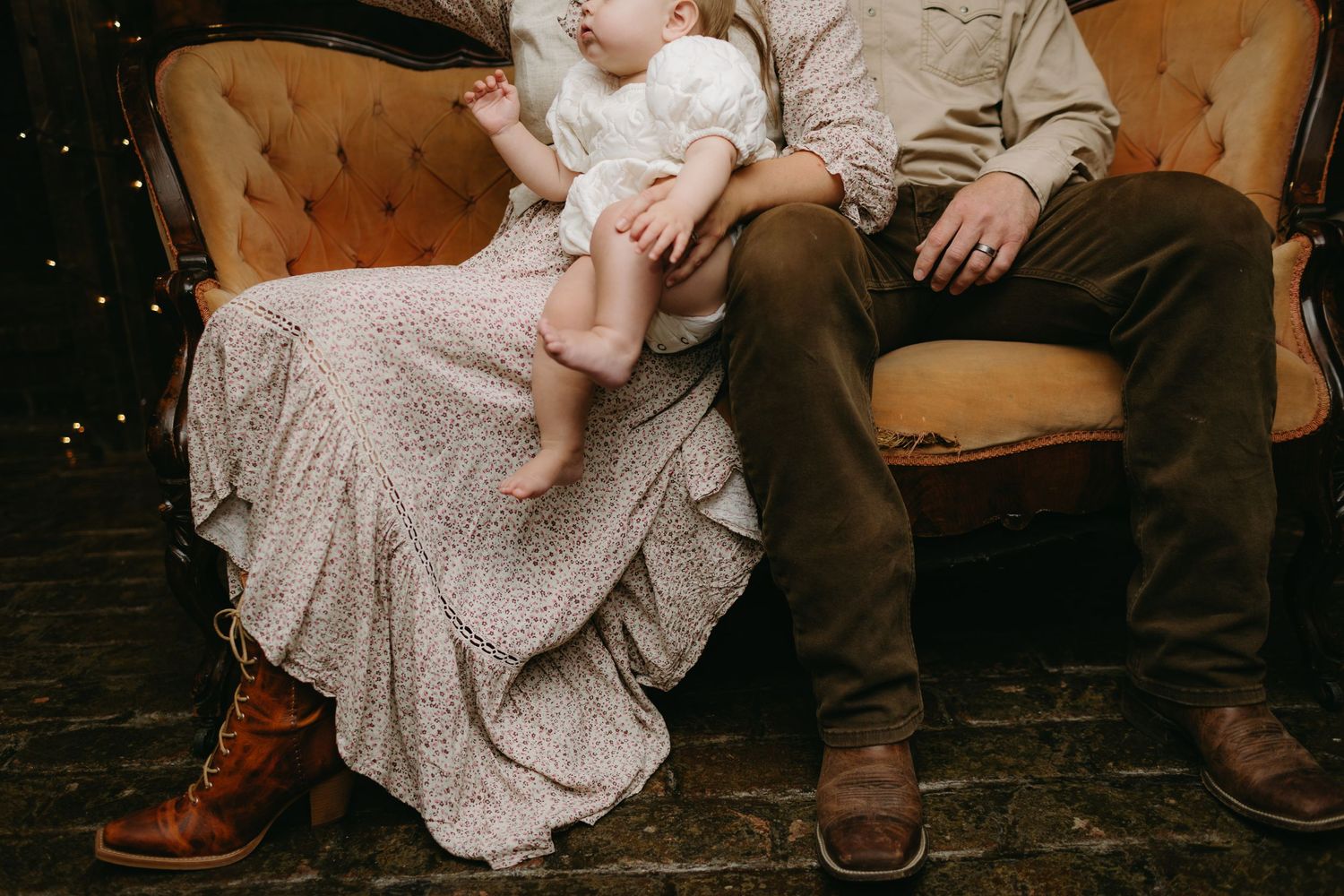 Intimate portrait on vintage brown couch with lace dress details.