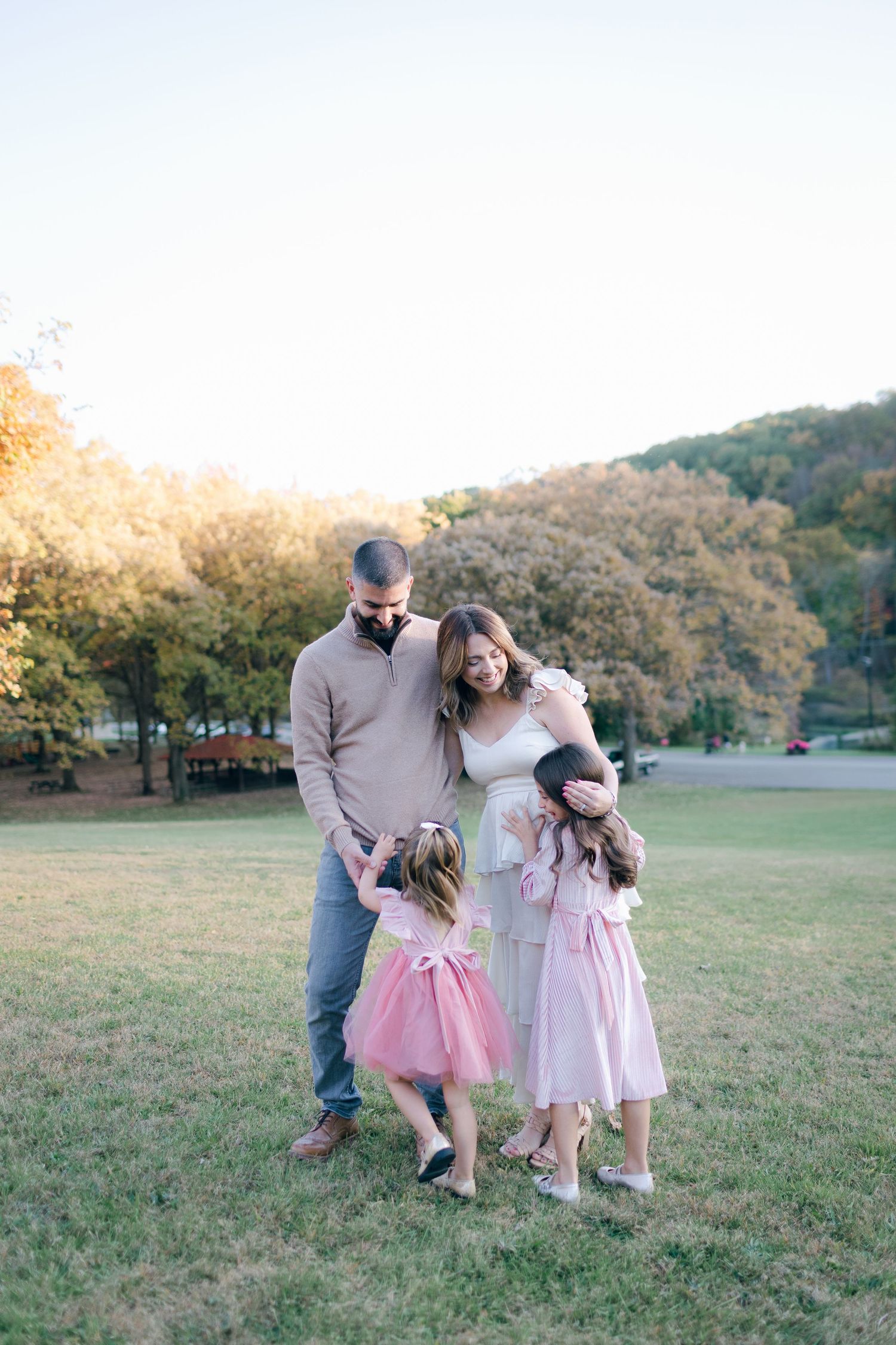 A family enjoying sunset outdoors in a field with autumn trees in the background.