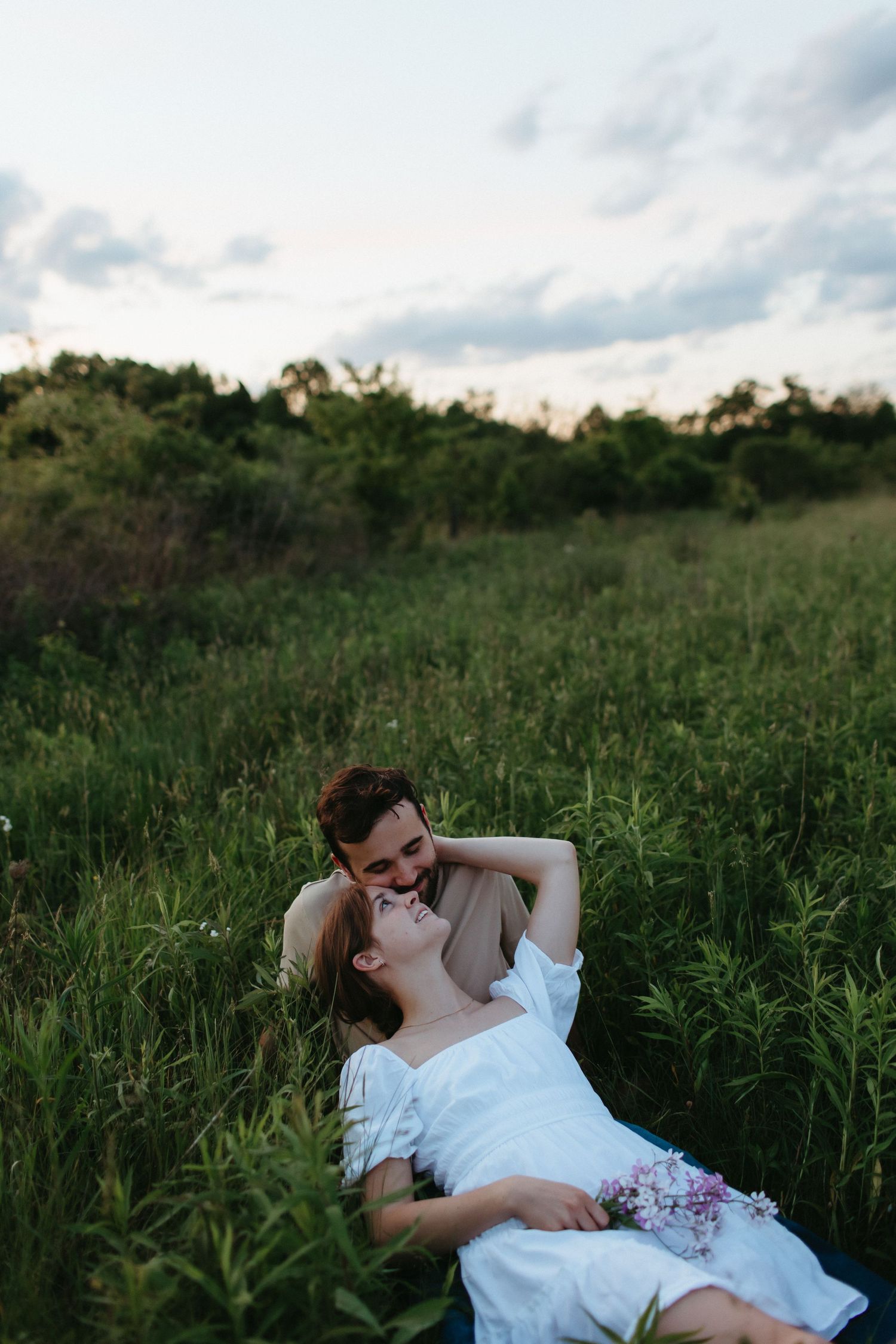 Romantic couple lying in tall grass enjoying a sunset moment together.