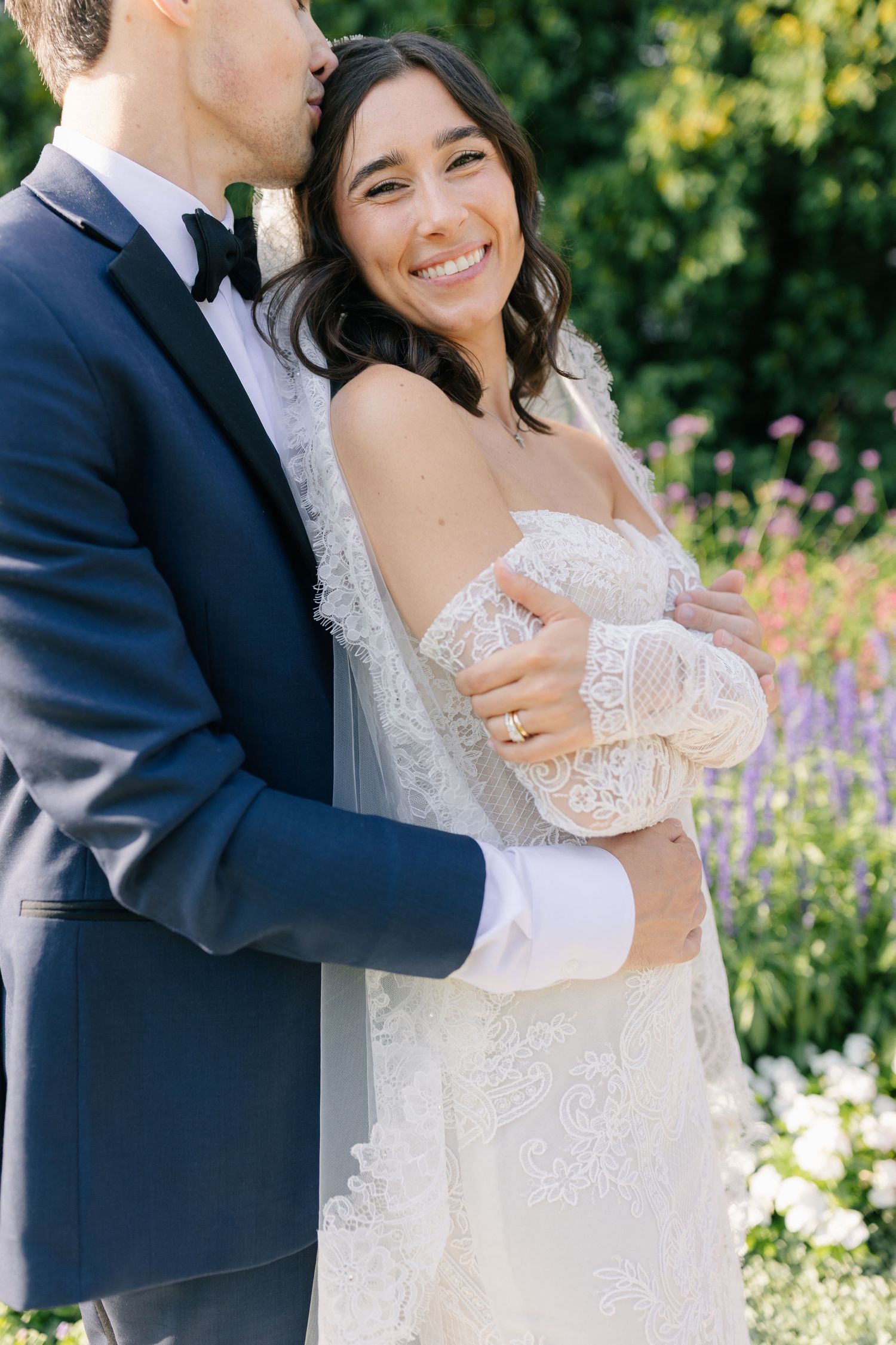 A romantic wedding portrait series of a couple embracing in a blooming garden with colorful flowers.