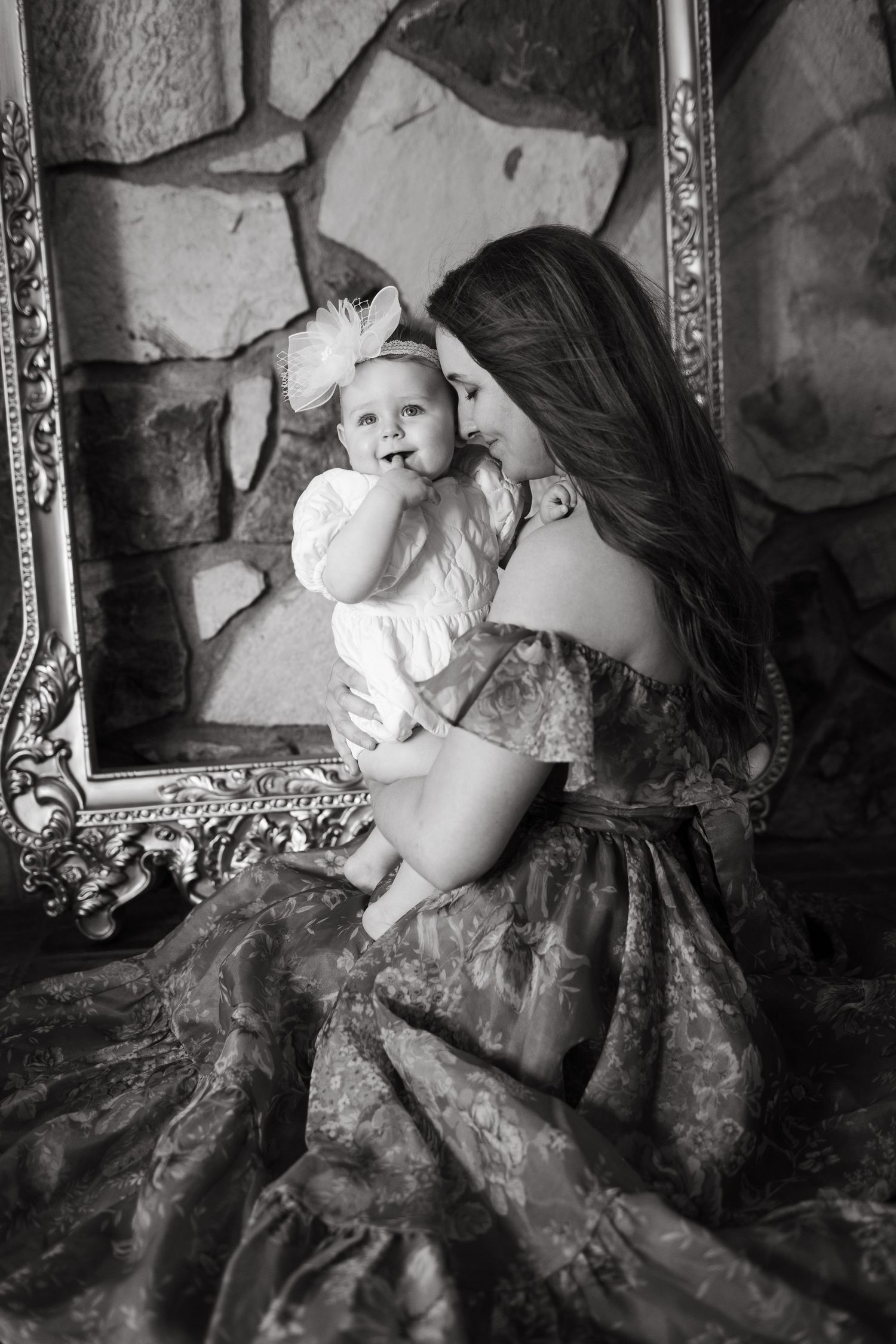 Black and white portrait against stone wall with ornate gold frame.