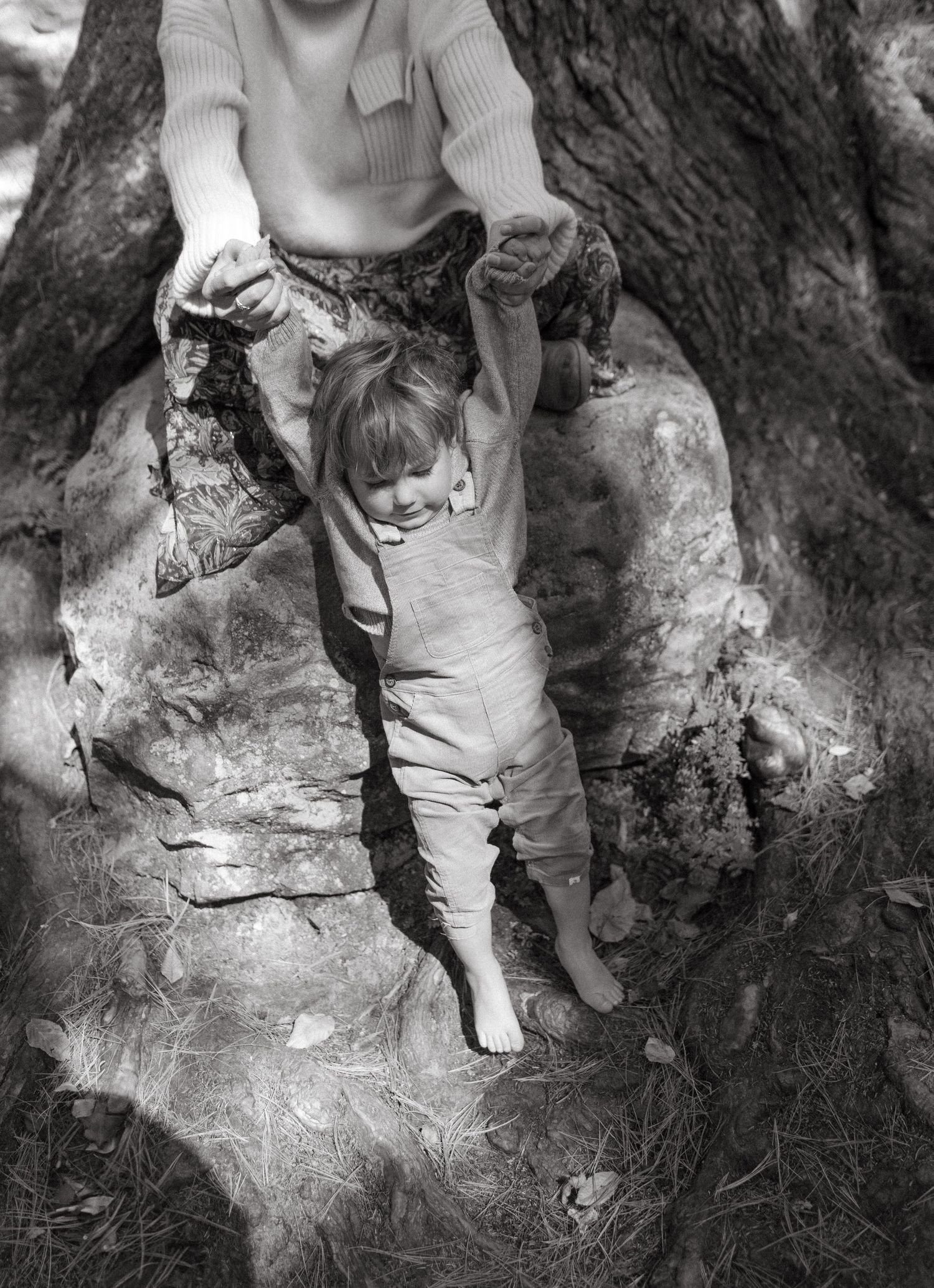 A black and white photo of support and play near a tree trunk.