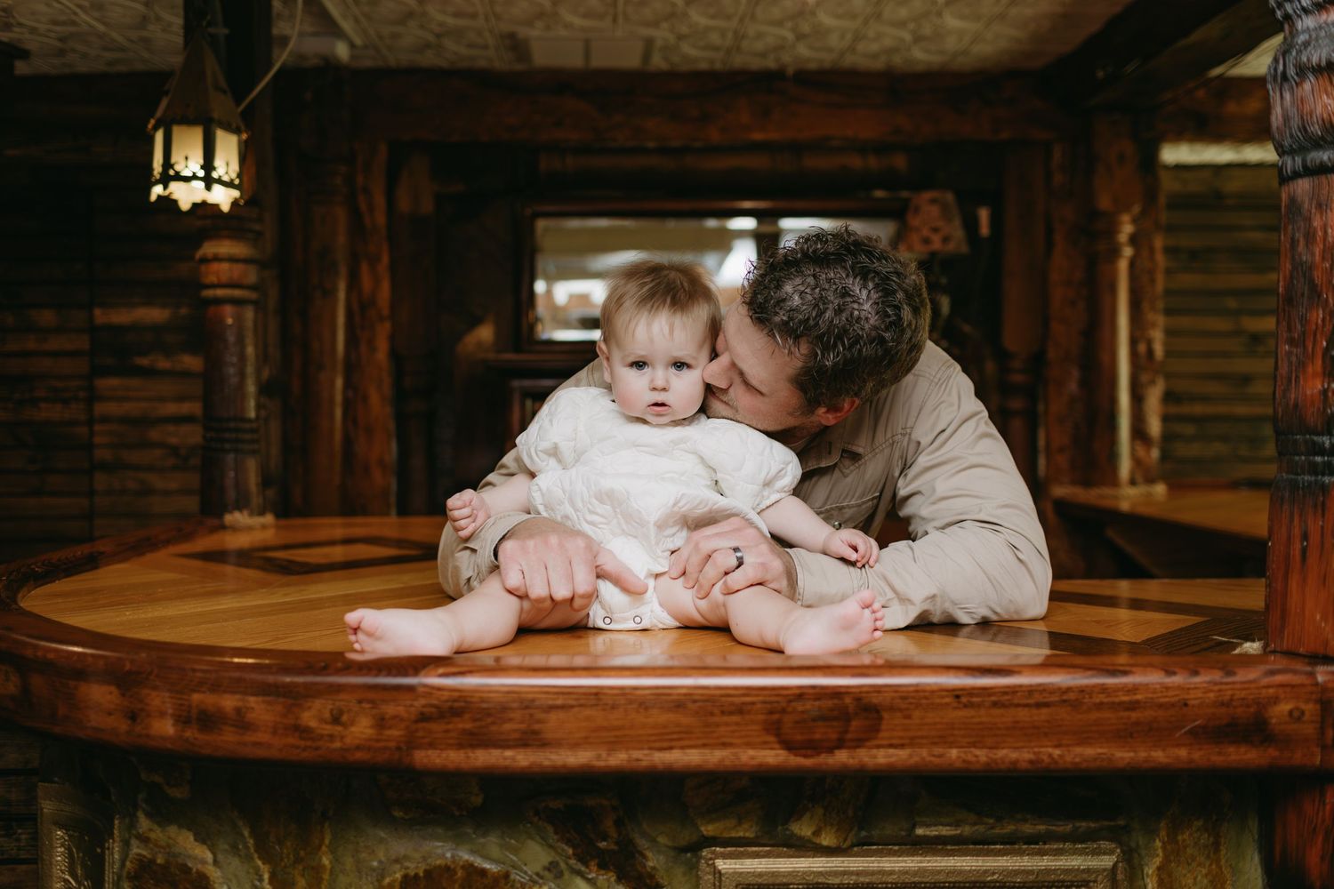 Tender moment shared on round wooden table in rustic indoor setting.