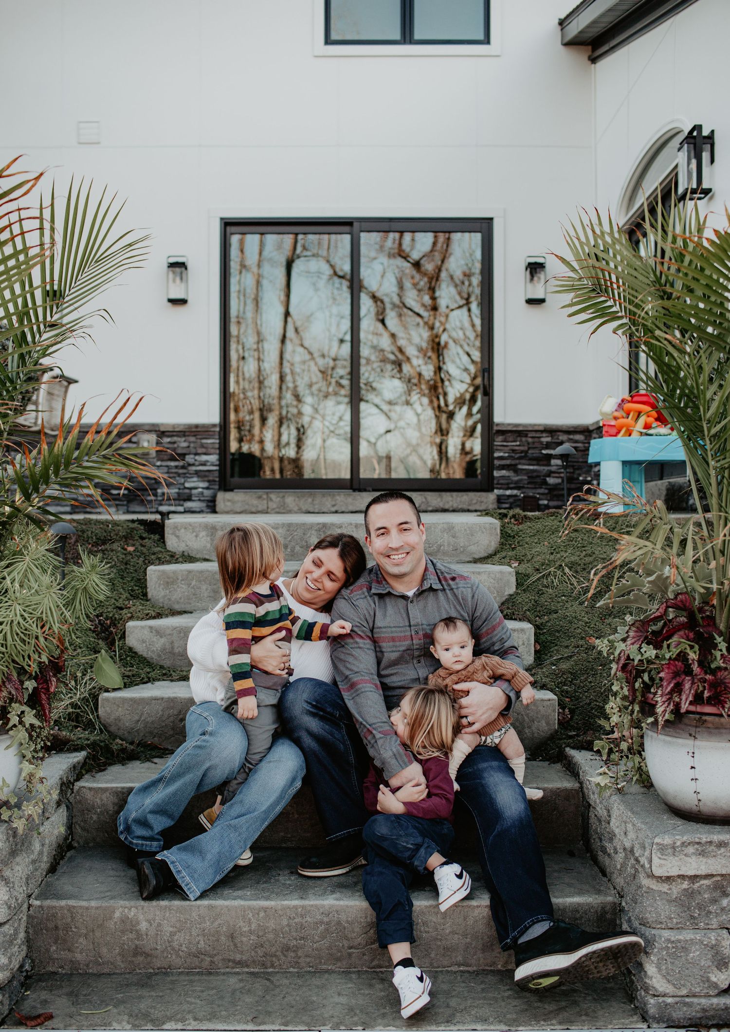 A family sitting together on outdoor stone steps with plants and decor.
