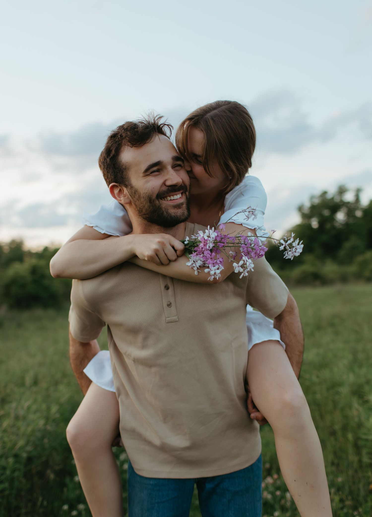 Playful piggyback ride in a wildflower meadow during golden hour.