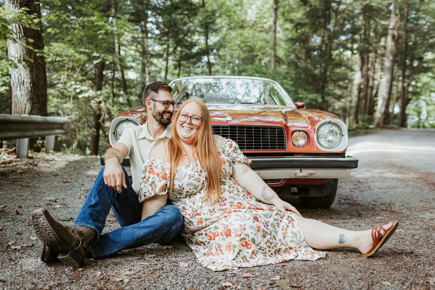 Casual photo session with a vintage red car in a wooded forest setting.