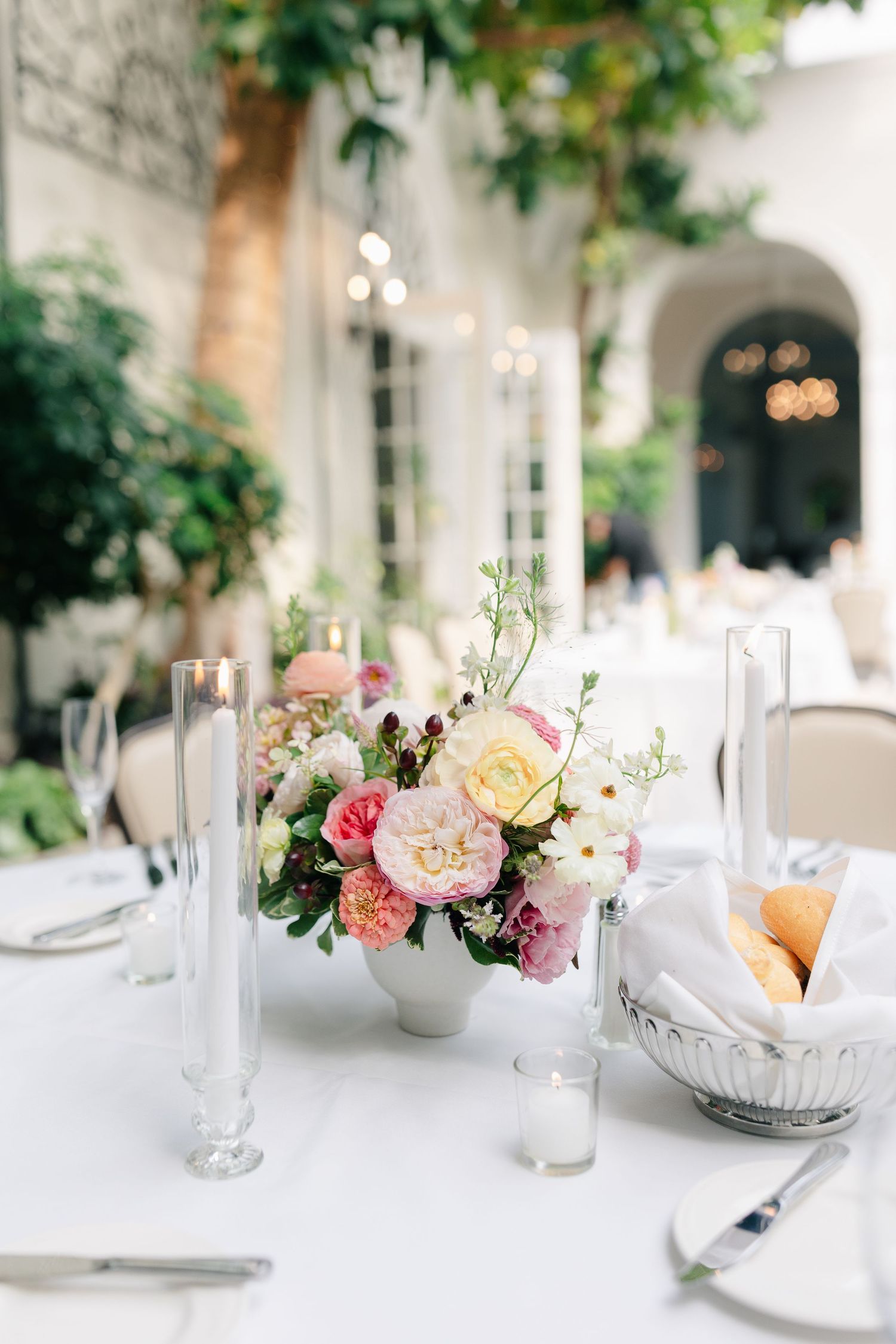 Romantic wedding table setting with pink and cream floral centerpiece and crystal glassware.