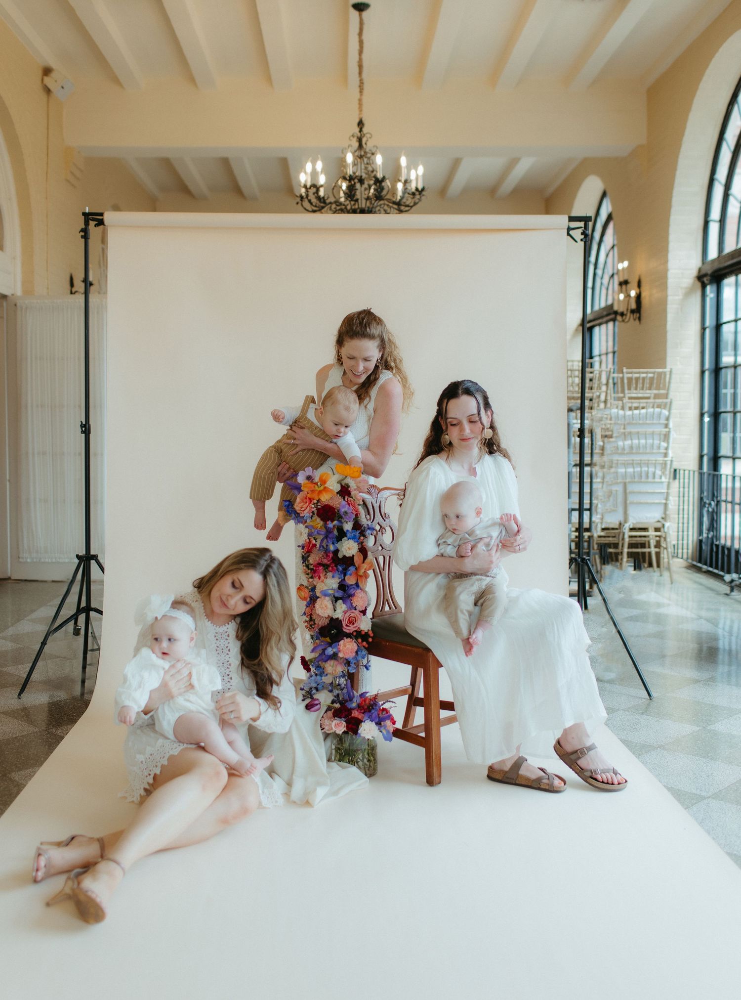 Group portrait in bright studio with white backdrop and elegant chandelier overhead.