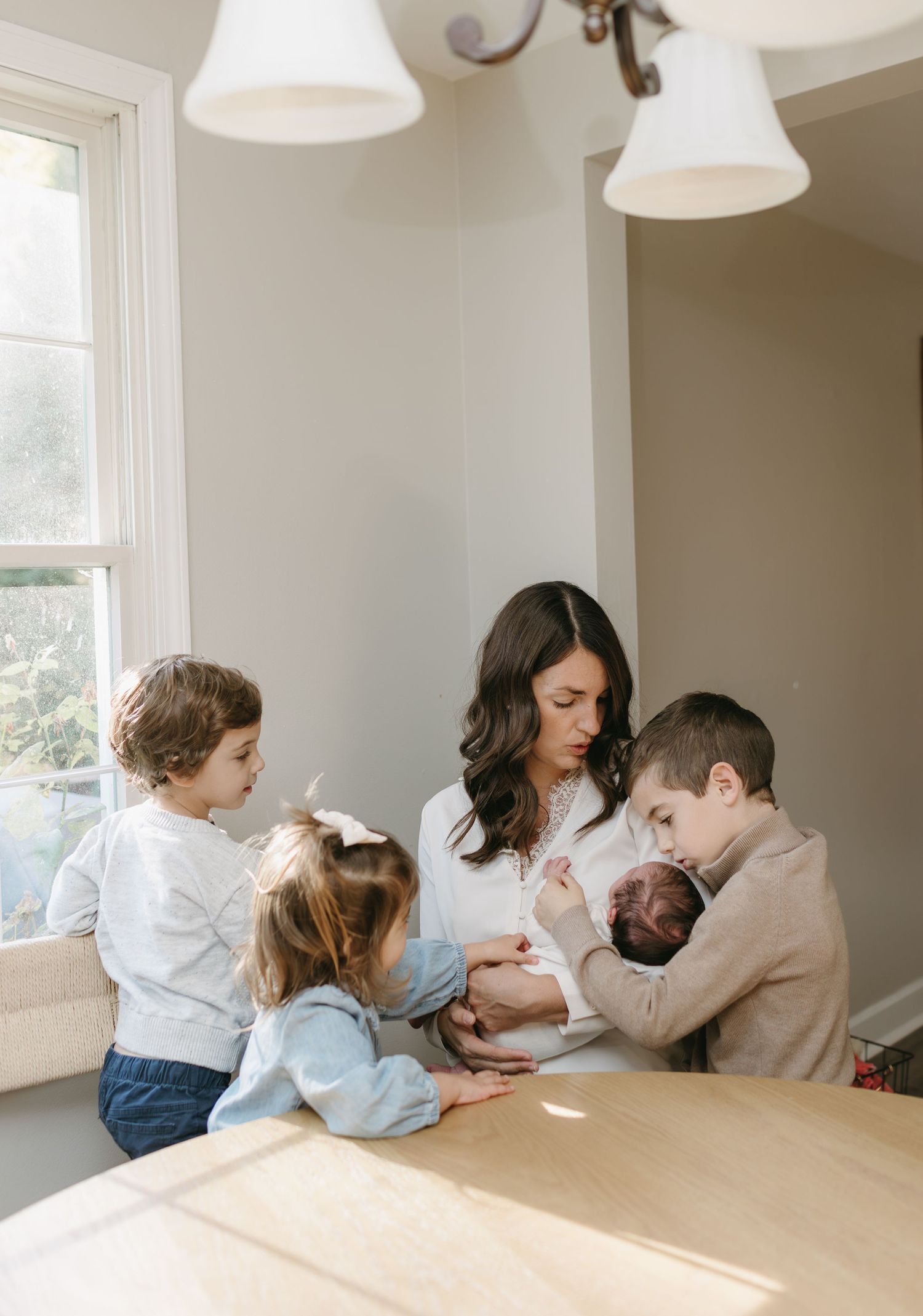 A family gathering around a table near a bright window in their home.