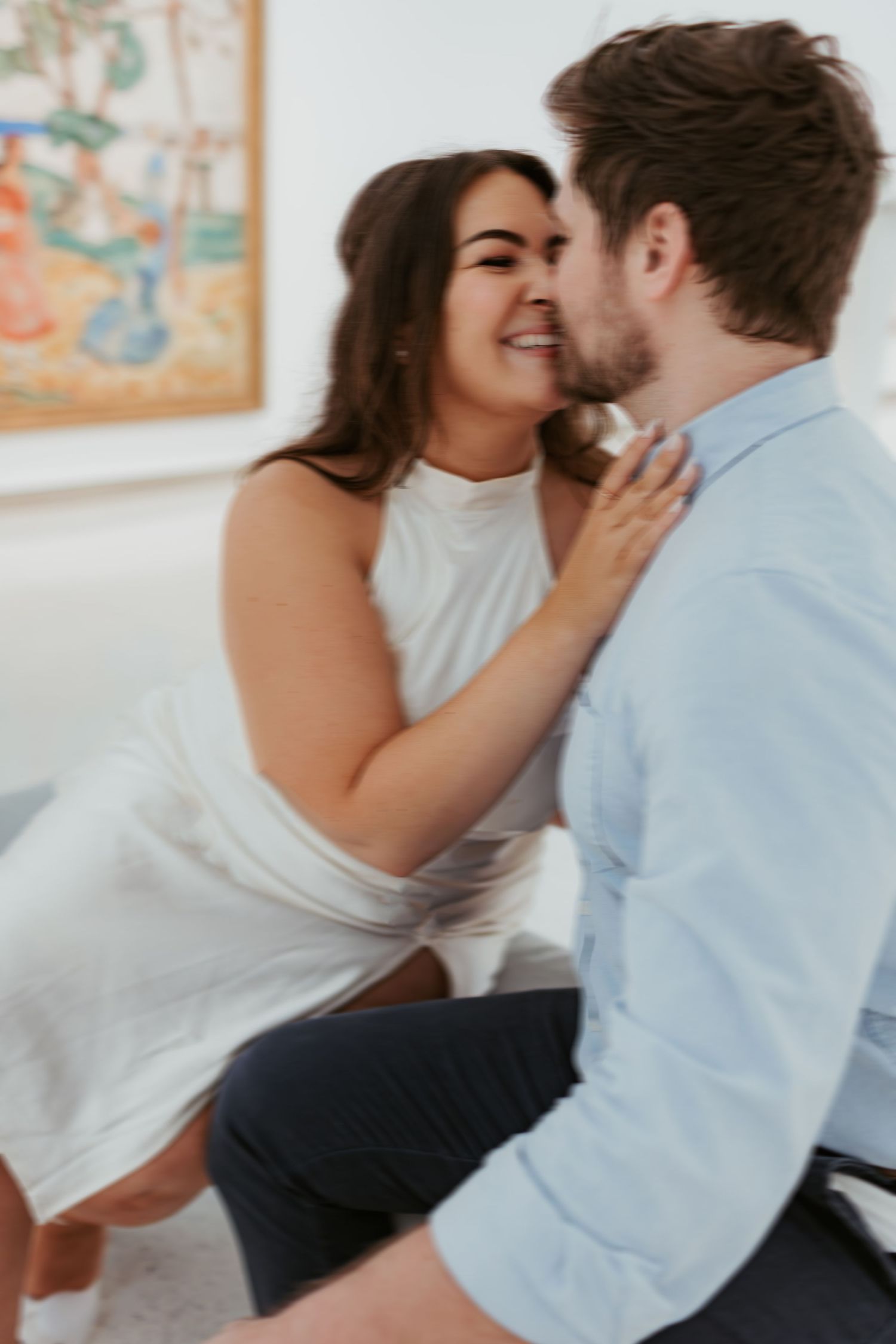 Intimate moment between couple in white and blue attire indoors.