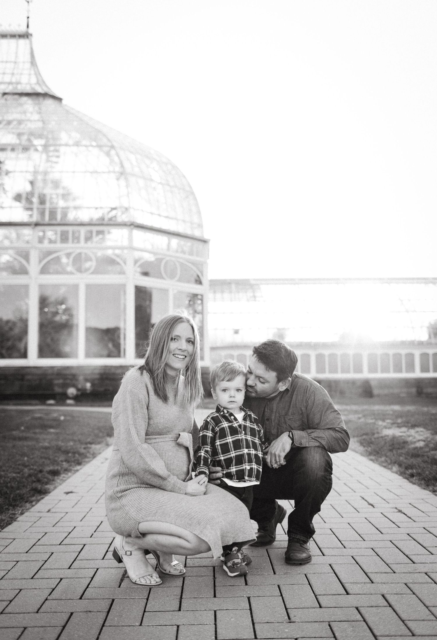 A family poses together in front of a historic domed building on a brick pathway.