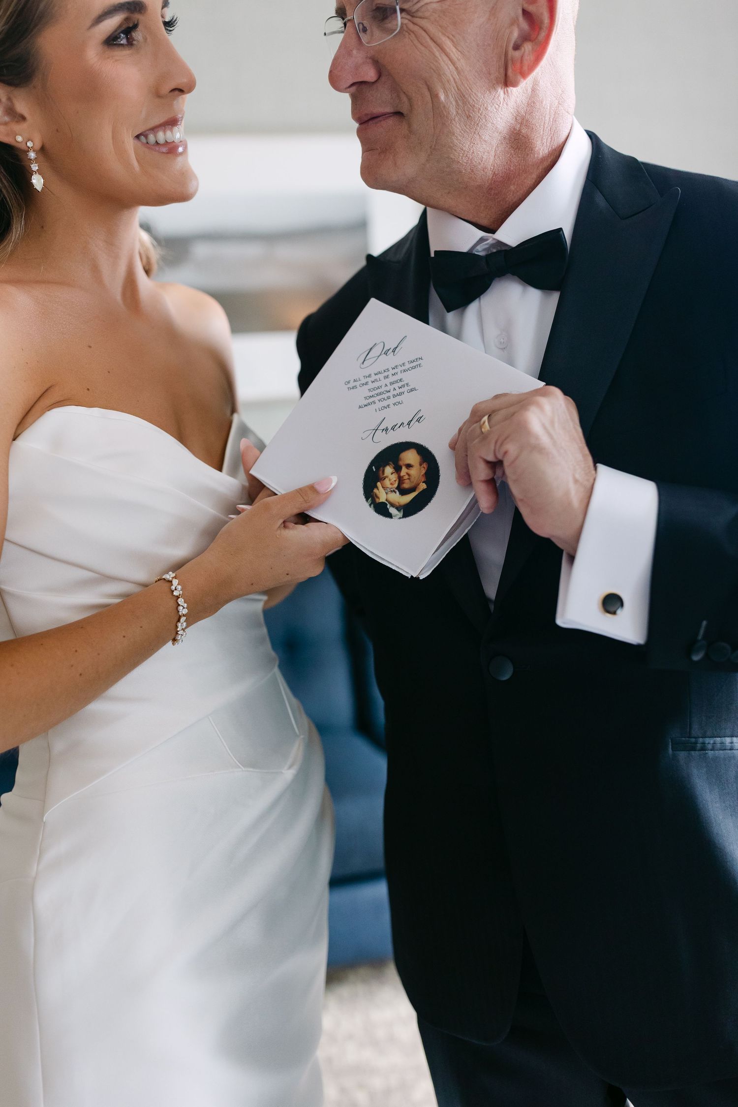 A tender moment captured as a bride and older man in formal attire share a special note with a seal.