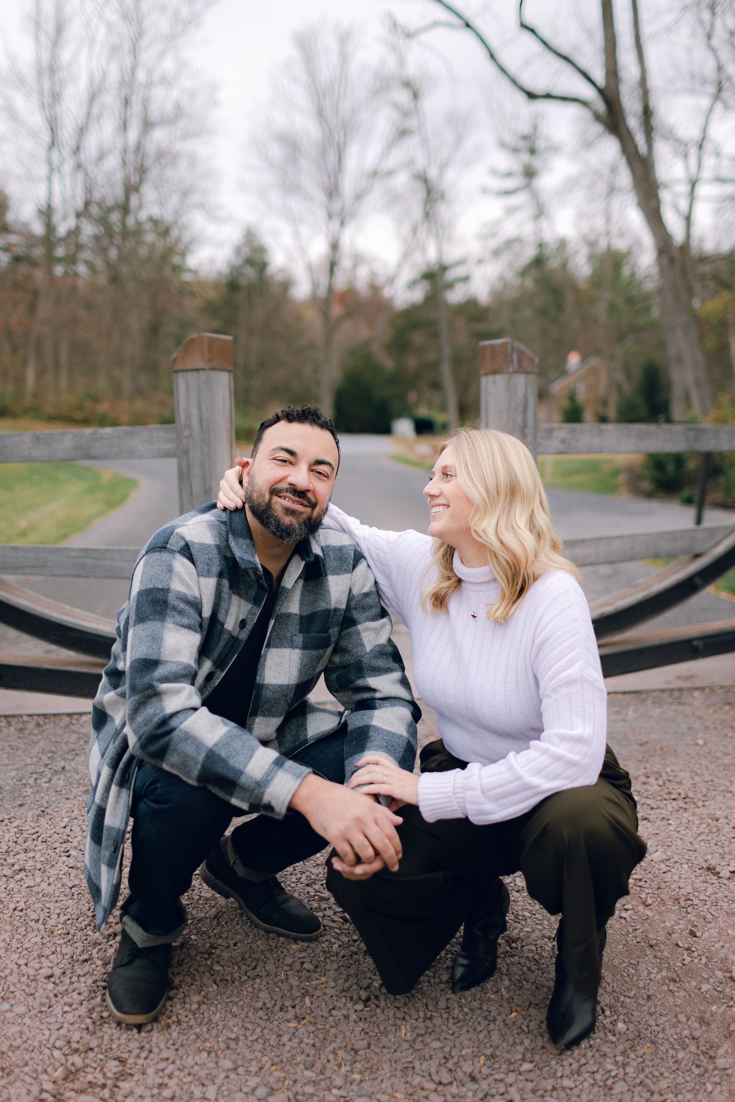 A couple crouches together on a path, sharing a happy moment outdoors.