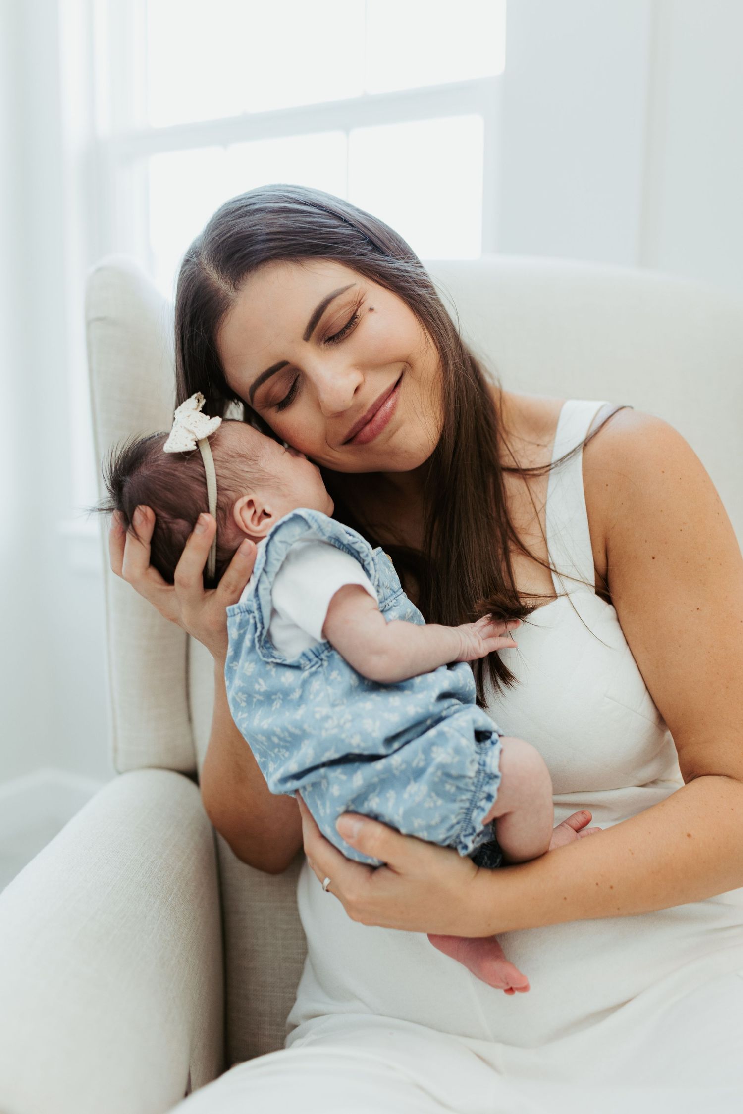 A tender moment between parent and infant in a bright white room.