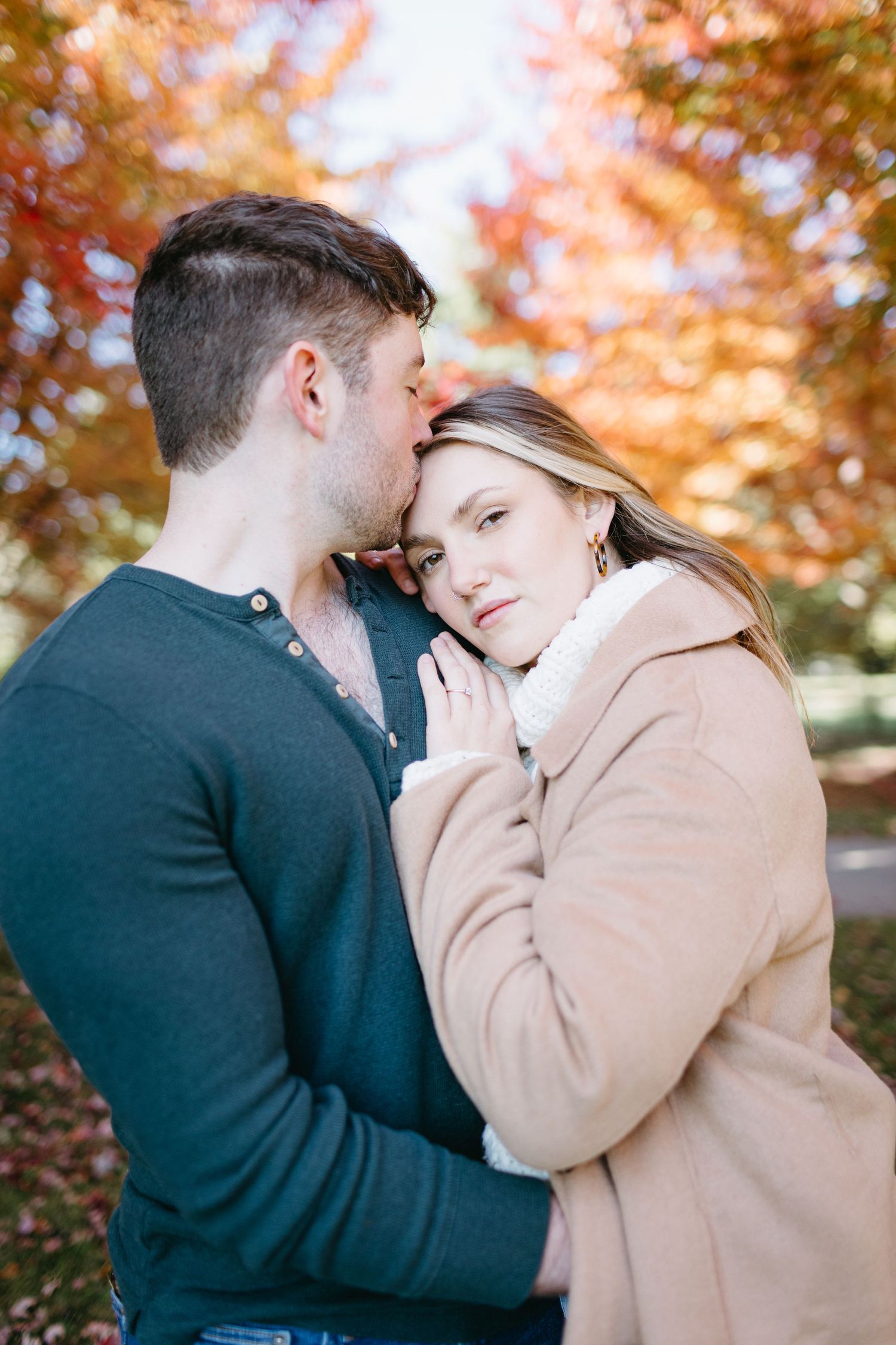 A romantic autumn moment between a couple surrounded by vibrant orange fall foliage.