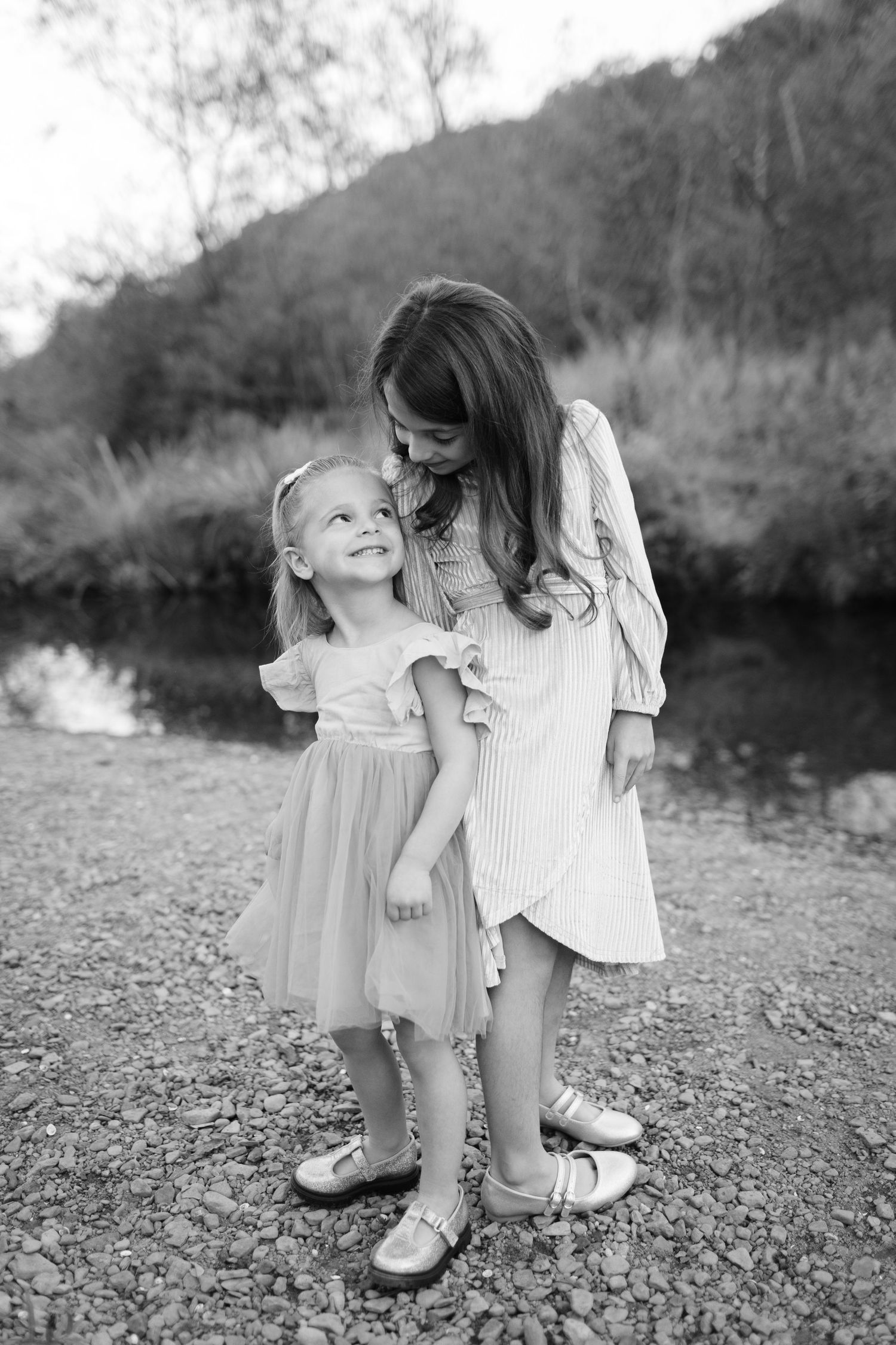 A tender outdoor moment by a river on a cloudy day.