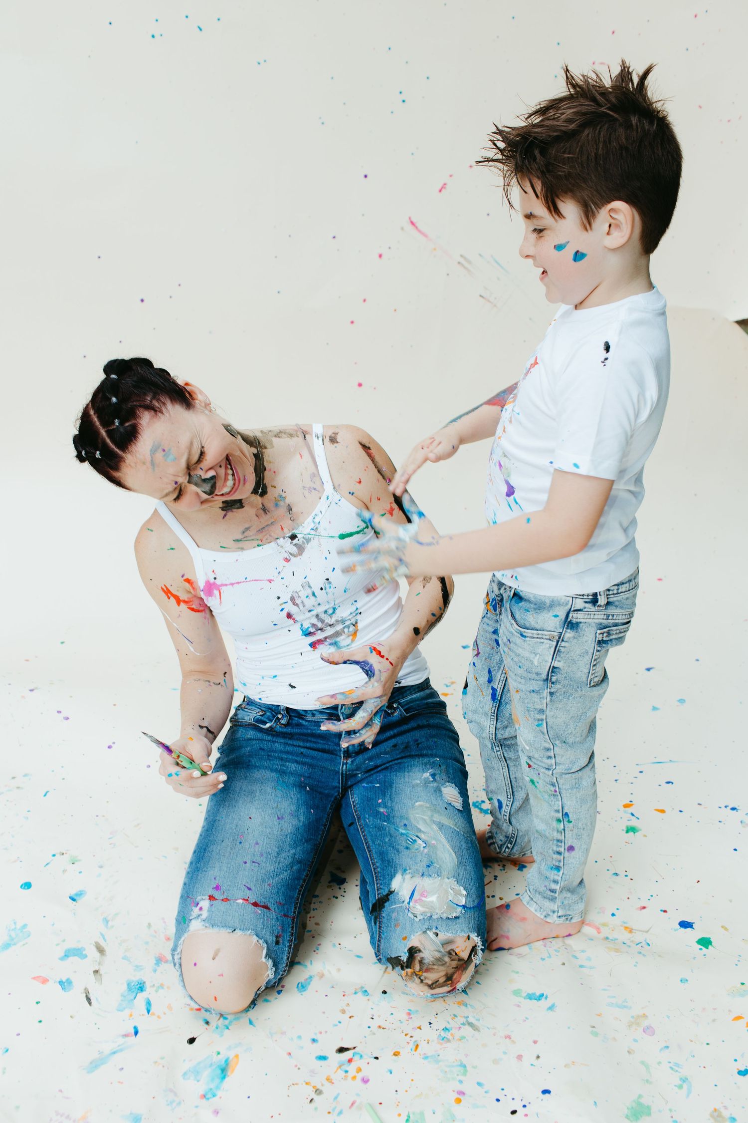 Playful paint mess photo session with splattered colors on white backdrop.