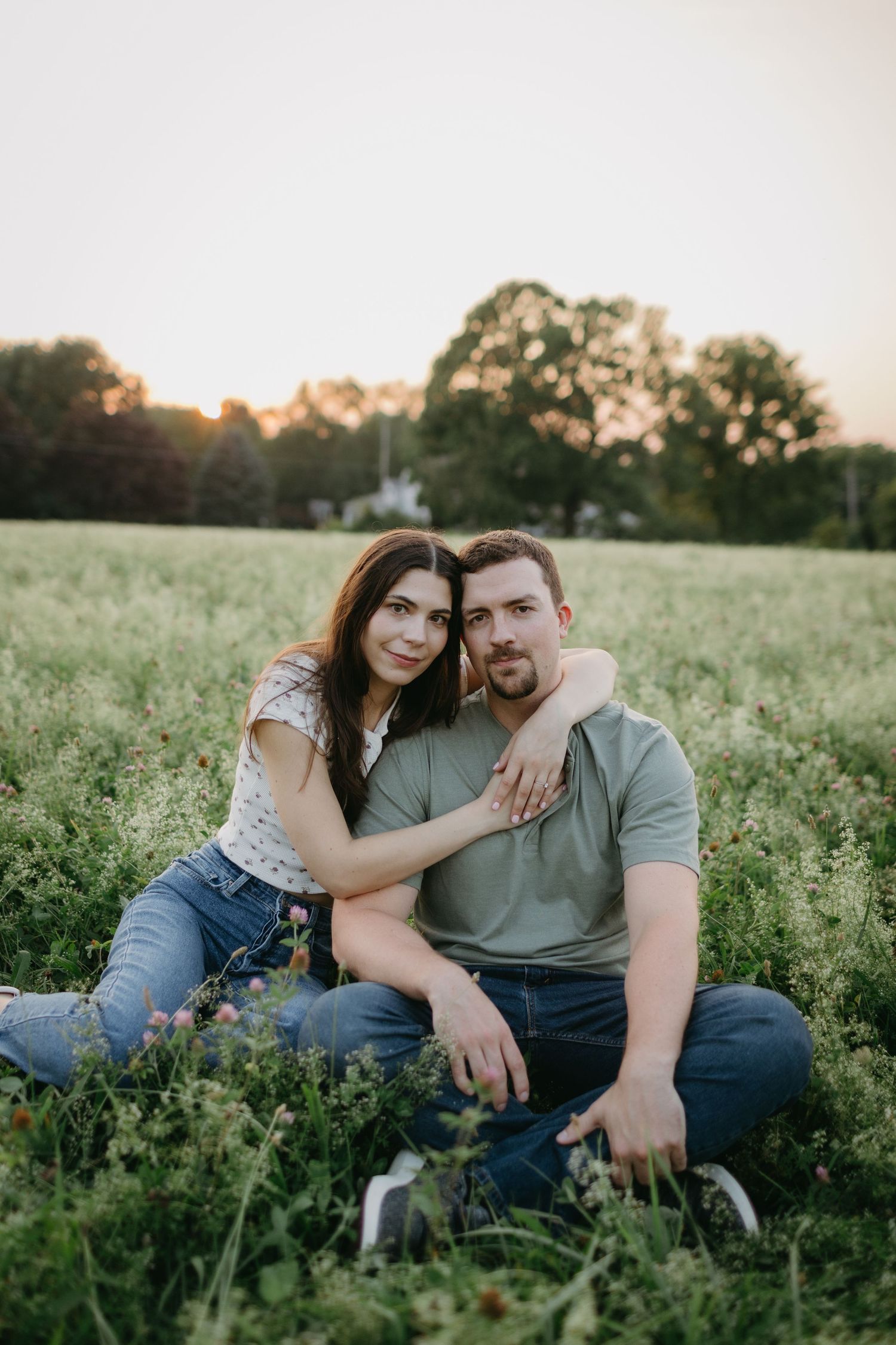 Couple sitting together in meadow during sunset.