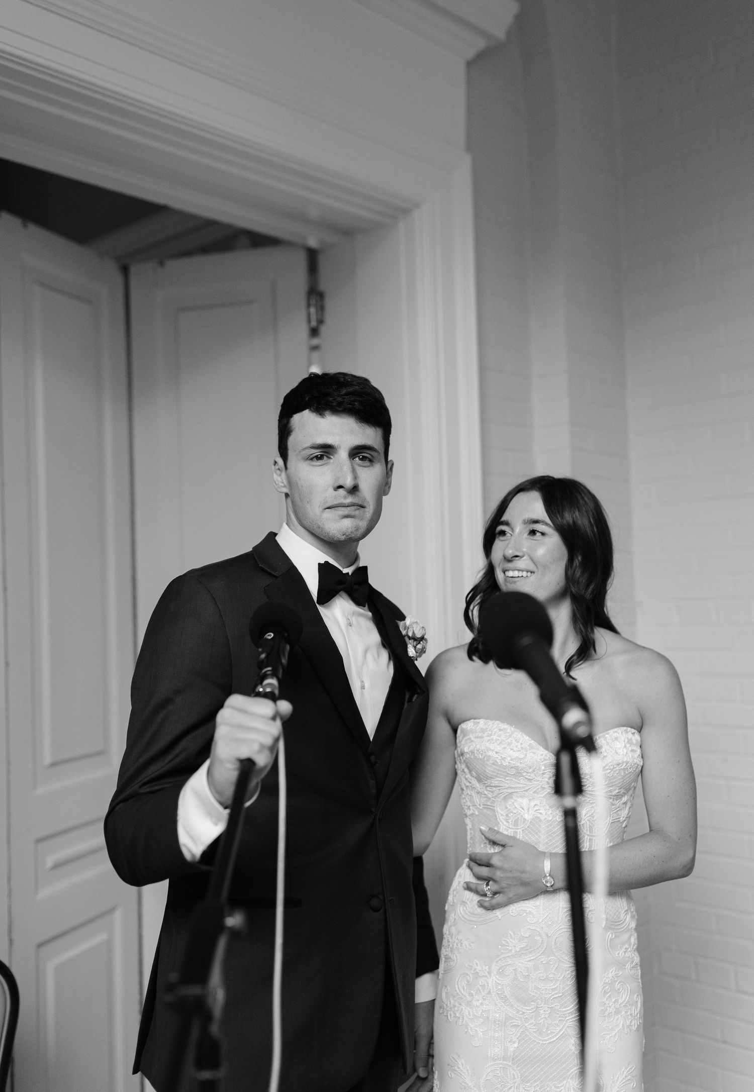Black and white wedding photos showing a couple posing playfully in an elegant indoor setting.