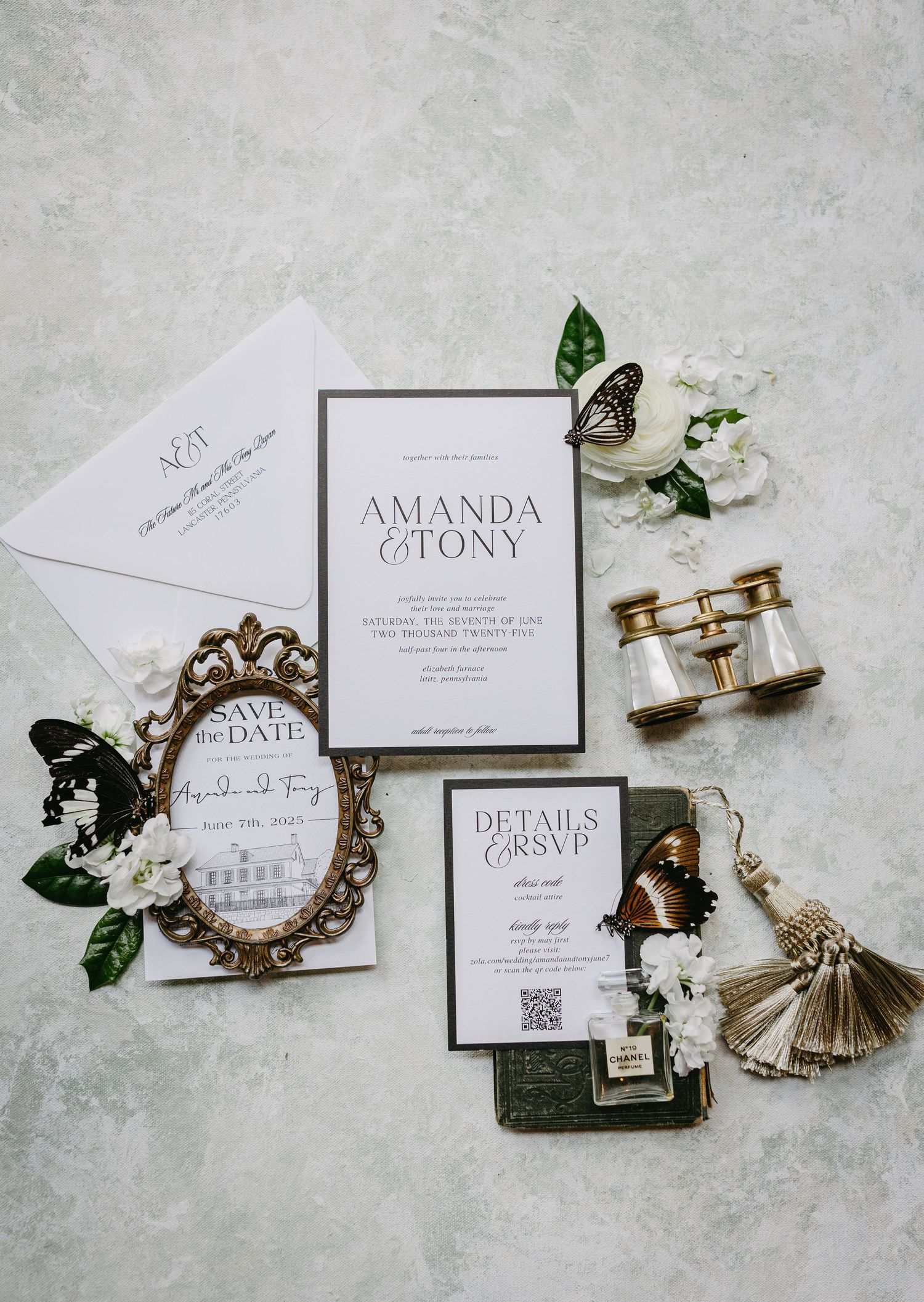 Elegant wedding invitation suite with vintage frame, antique binoculars, floral accents and details card on light gray surface.