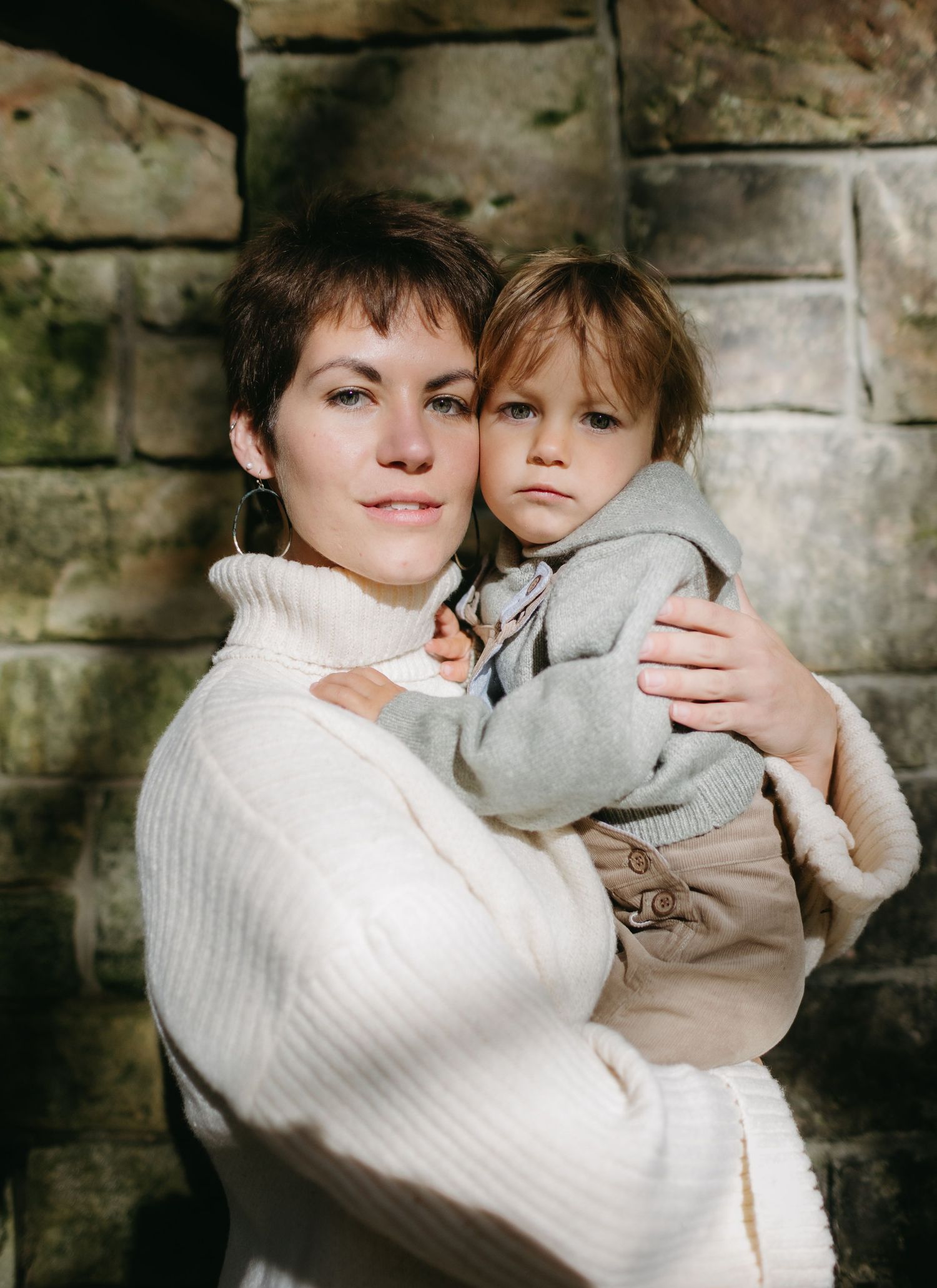 A warm autumn portrait against a stone wall featuring neutral cream and gray tones.