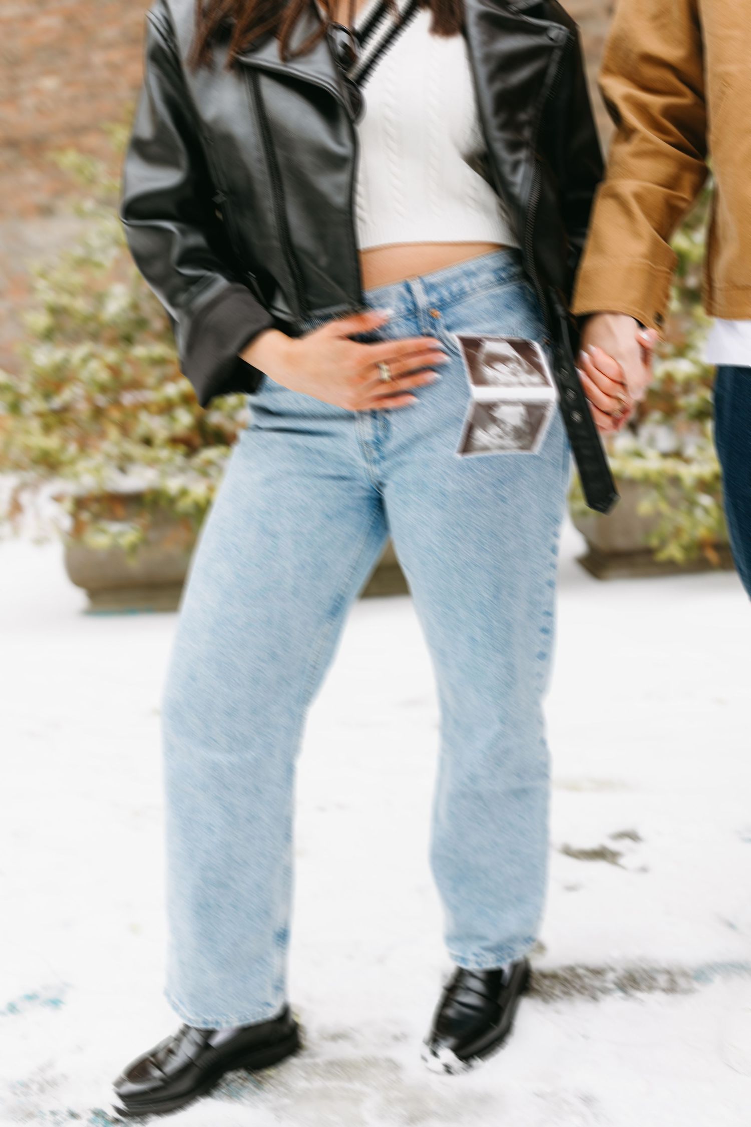 Close-up of denim jeans and leather jackets with an ultrasound photo visible in the pocket.