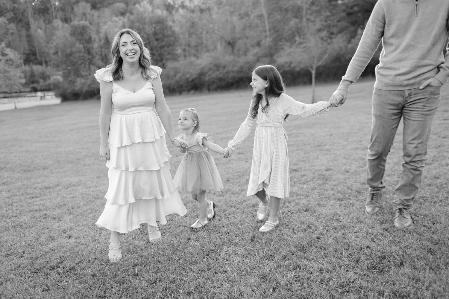 A family walking together on grass in black and white.