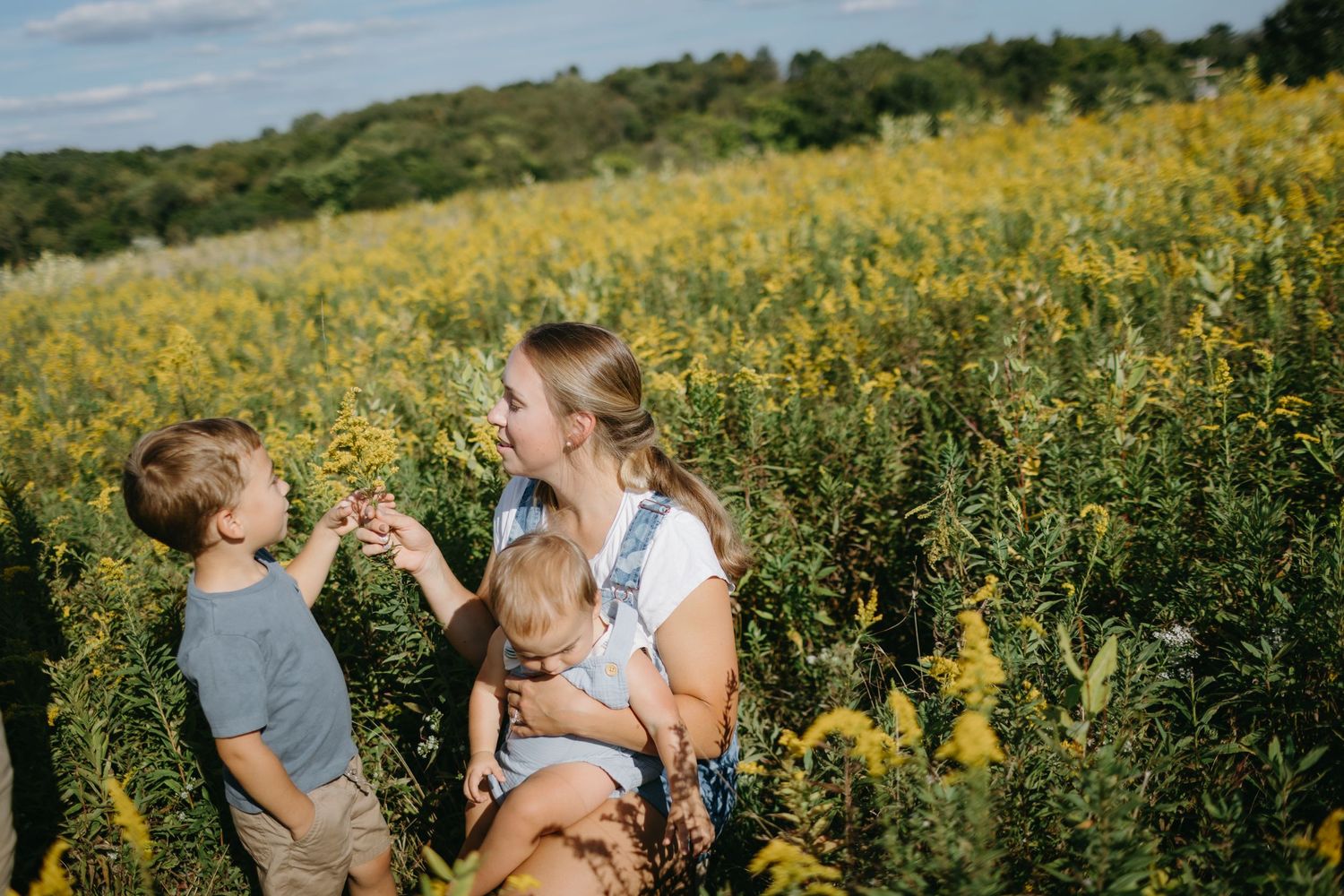 Family sharing playful moment in field of yellow wildflowers on sunny day.