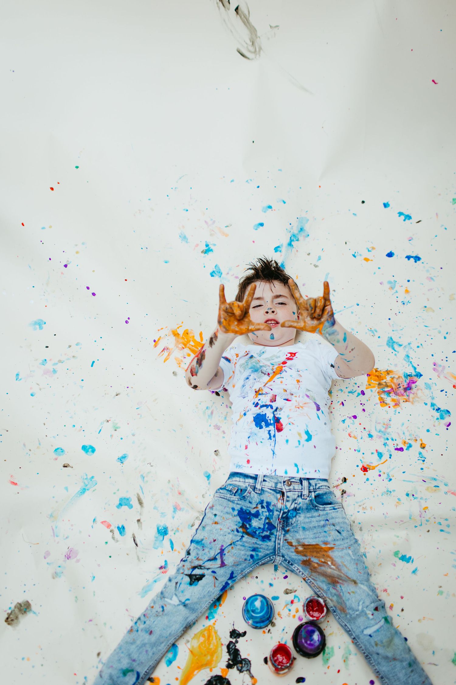 Creative portrait with colorful paint splatters against white background.