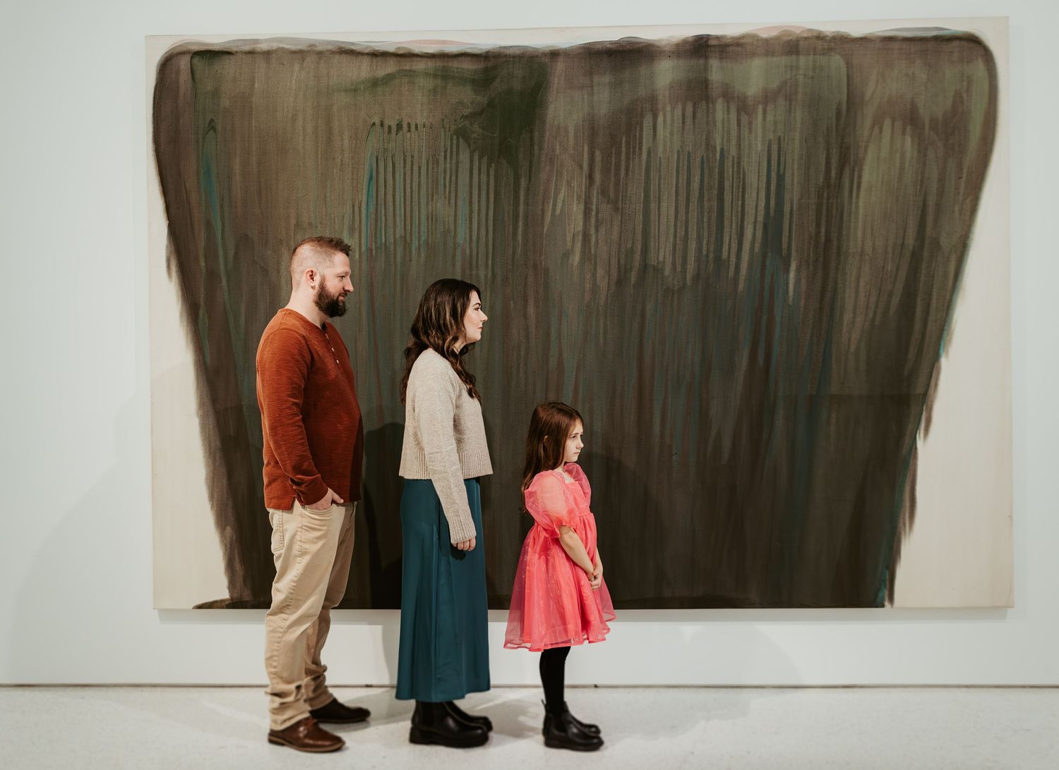 Three people viewing large abstract artwork in modern gallery space.