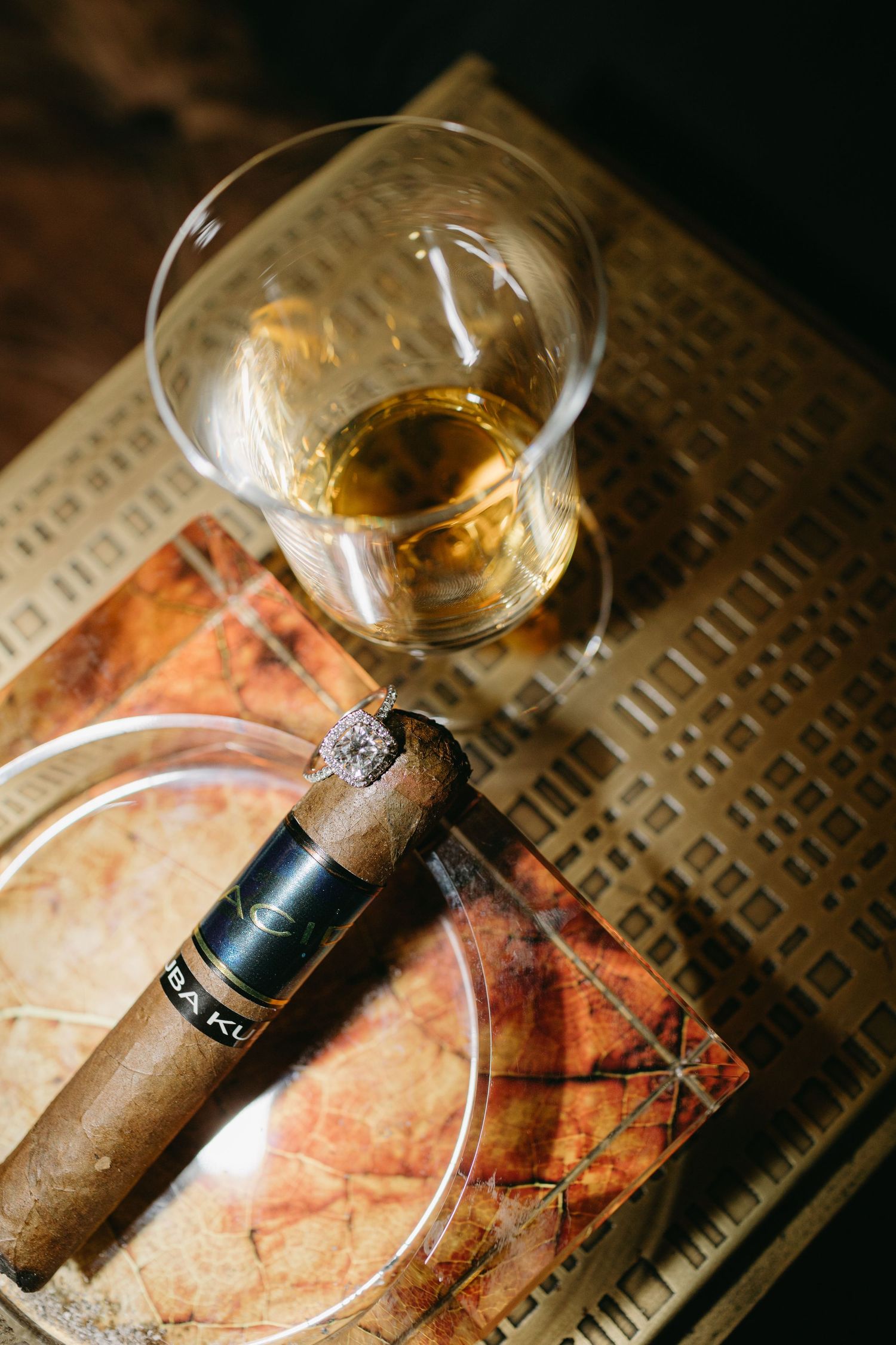 Glass of whiskey and cigar on vintage book with warm lighting.