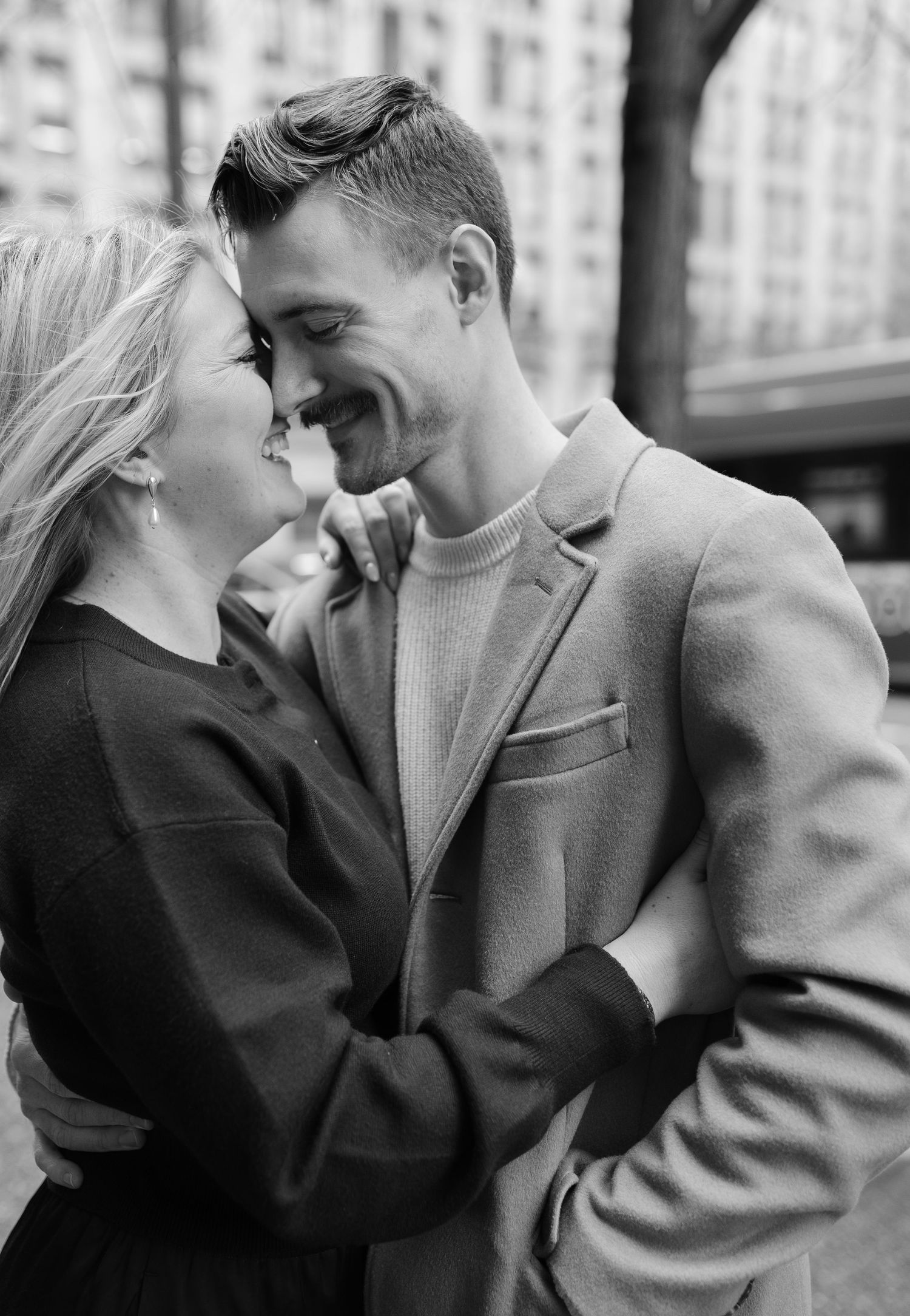 A romantic black and white photo series showing a couple in an intimate embrace against an urban backdrop.