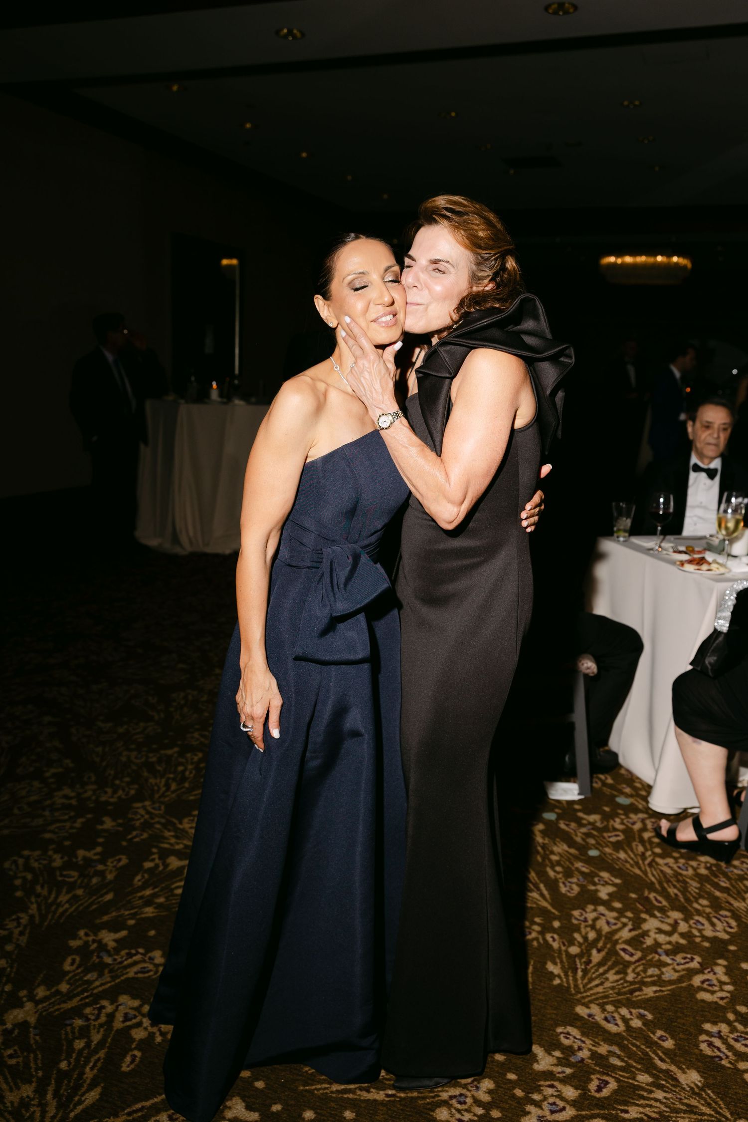 Two people in formal attire share a joyful moment dancing together at an elegant indoor event.