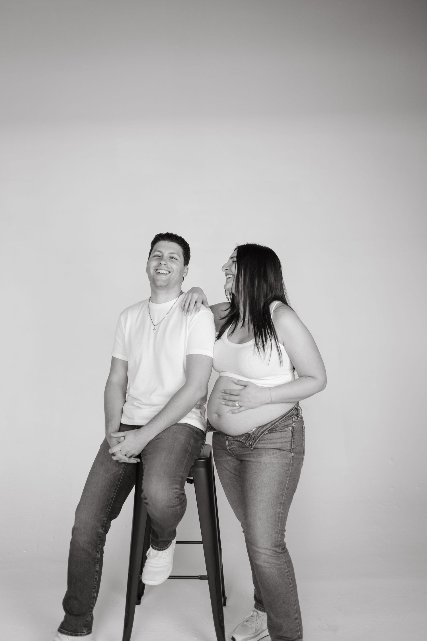 Black and white portrait of couple sharing intimate moment during maternity photoshoot.