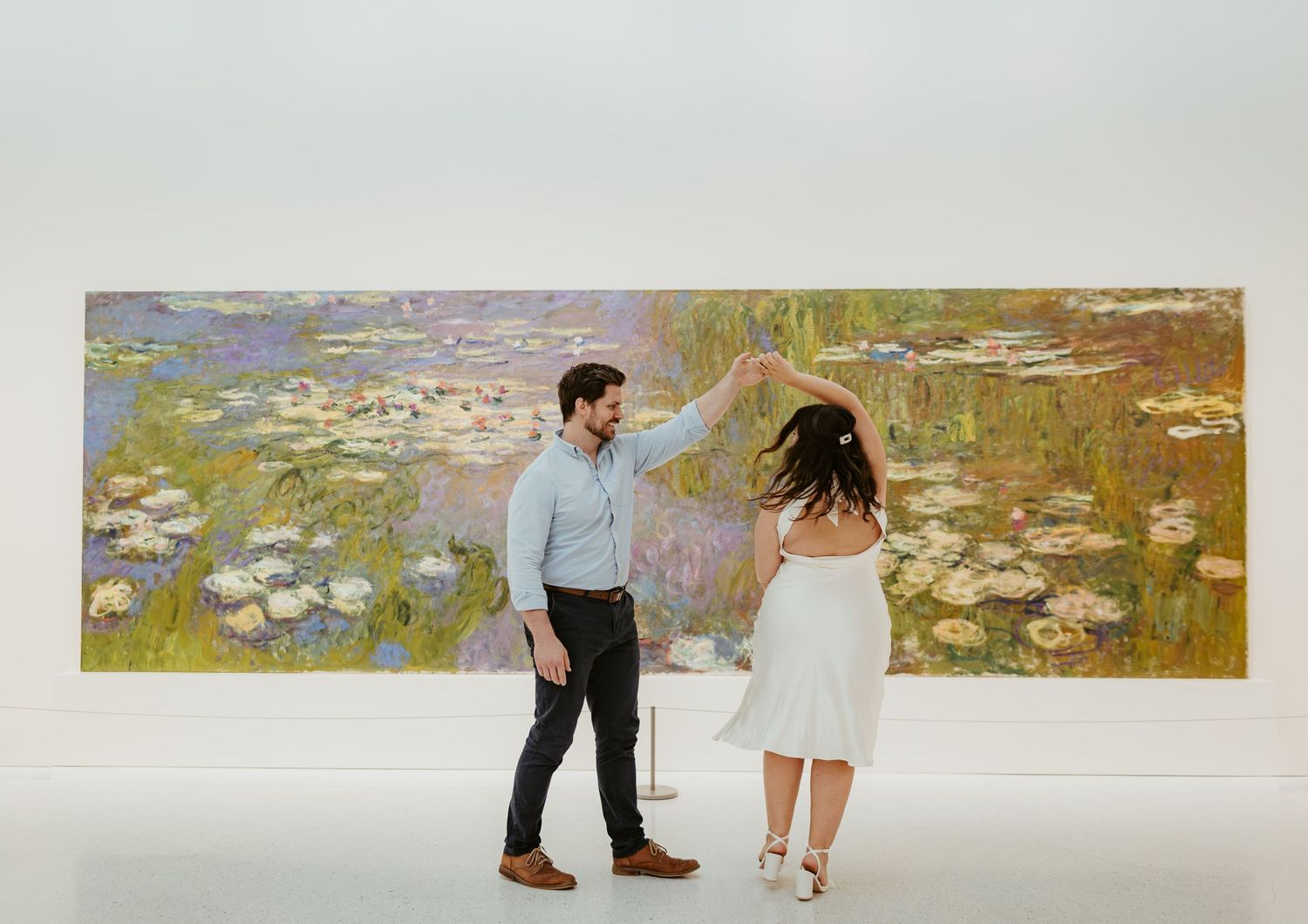 Couple dancing in front of Monet's water lilies painting in art gallery.