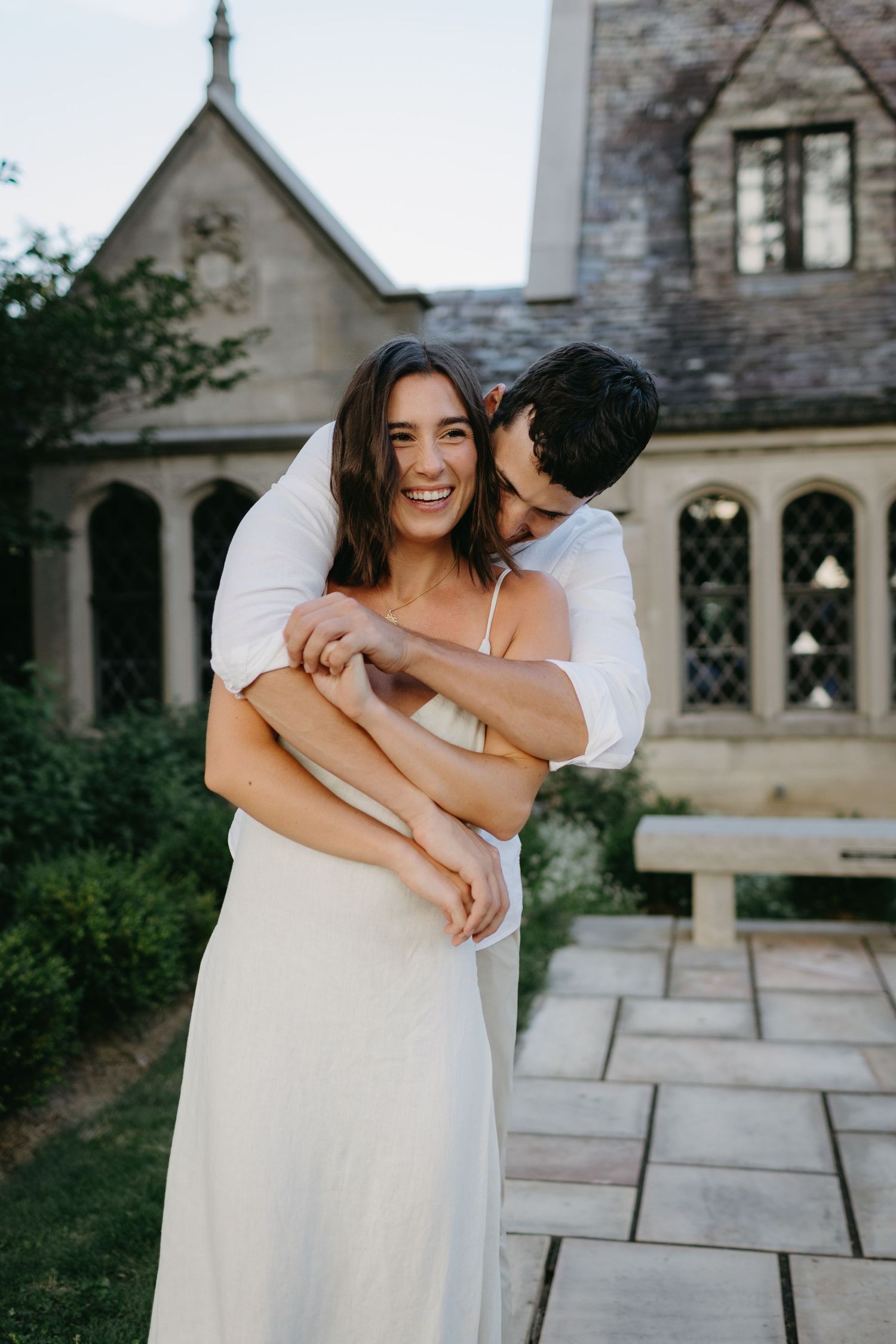 Joyful moment captured between couple in white outside gothic stone church building.