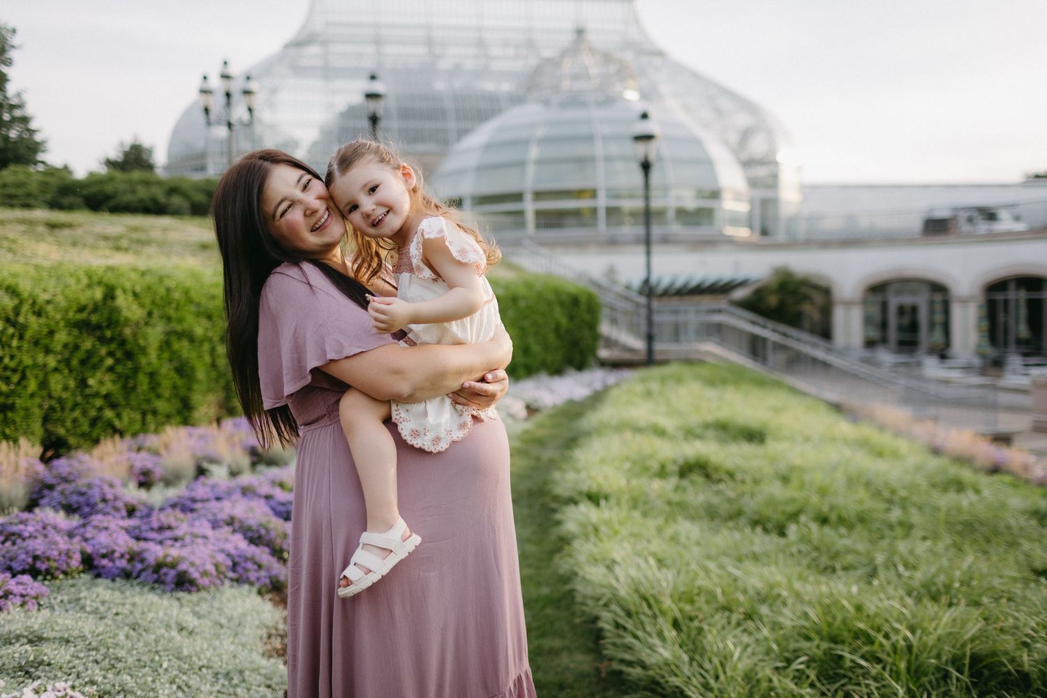 Joyful moment in front of greenhouse with blooming purple flowers.