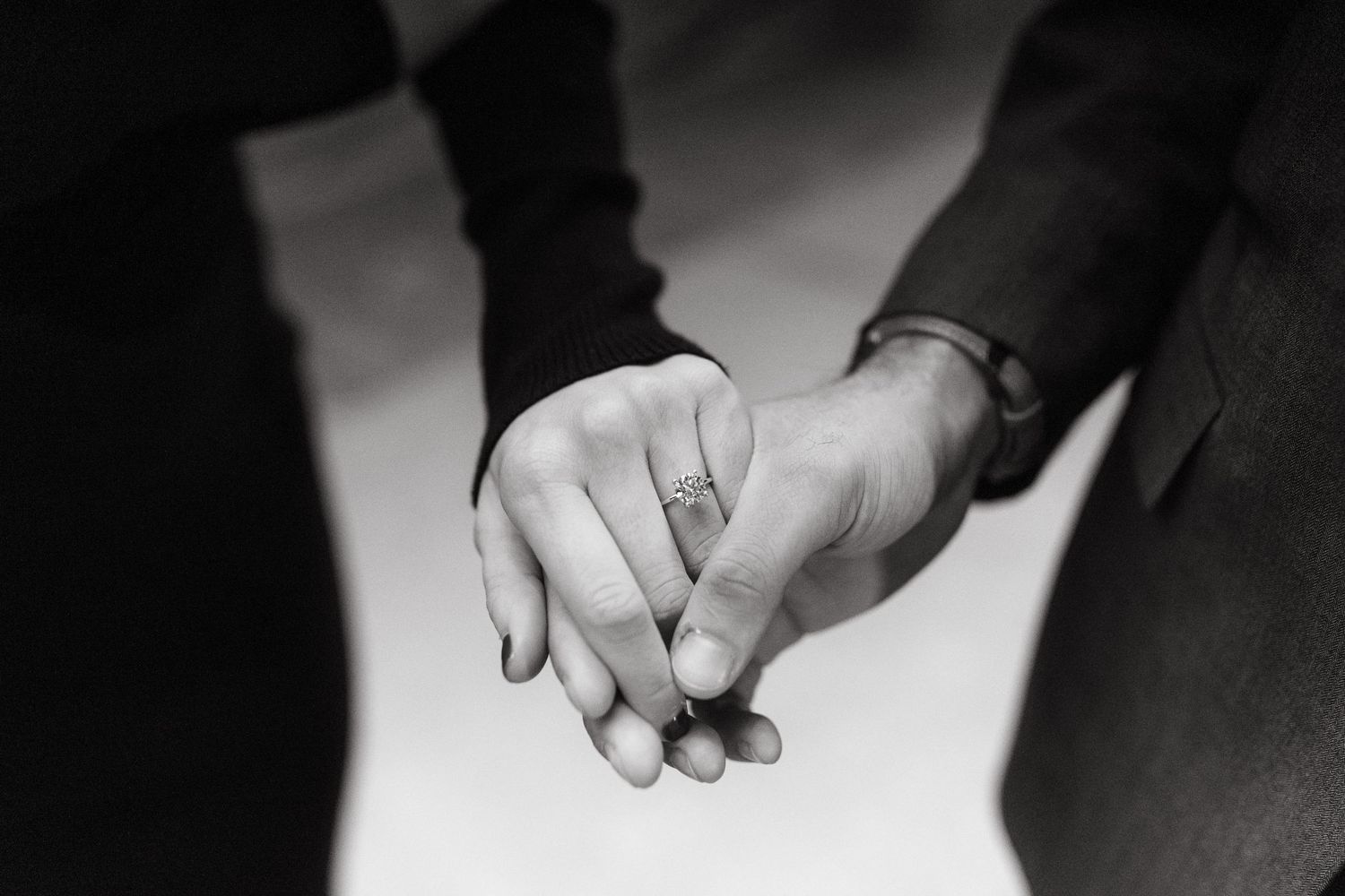 Black and white close-up of two hands tenderly holding each other.