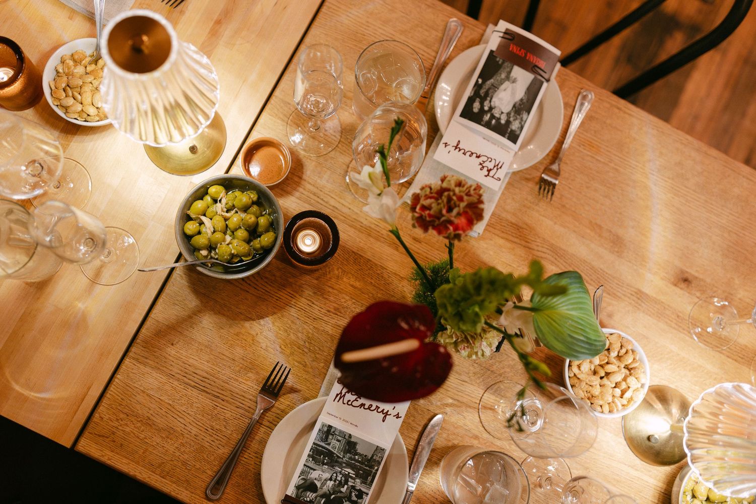 An elegant table setting at a wine tasting event with glasses, bottles, and appetizers in warm lighting.