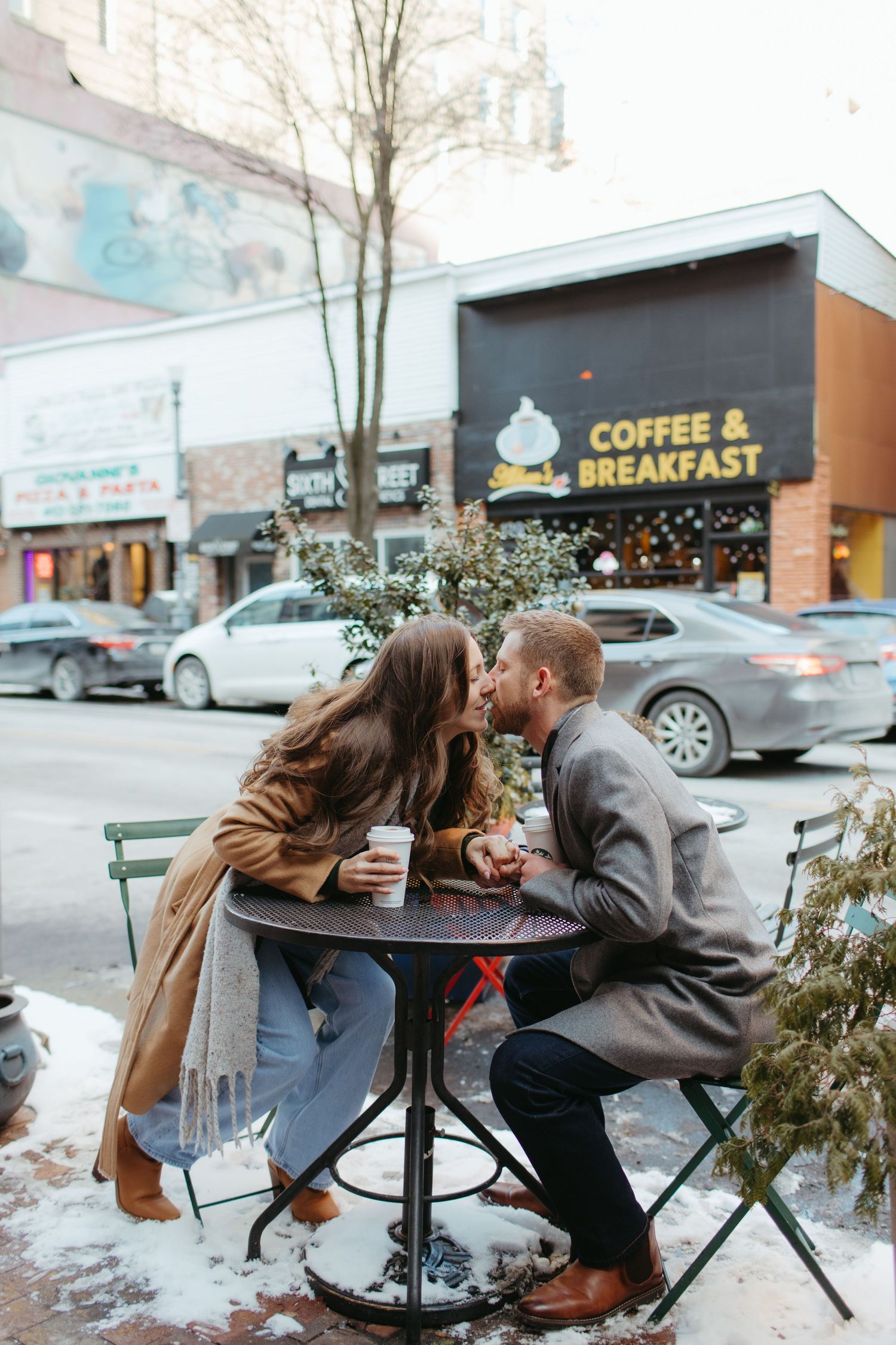 Couple sharing a romantic moment at an outdoor coffee shop table in winter.