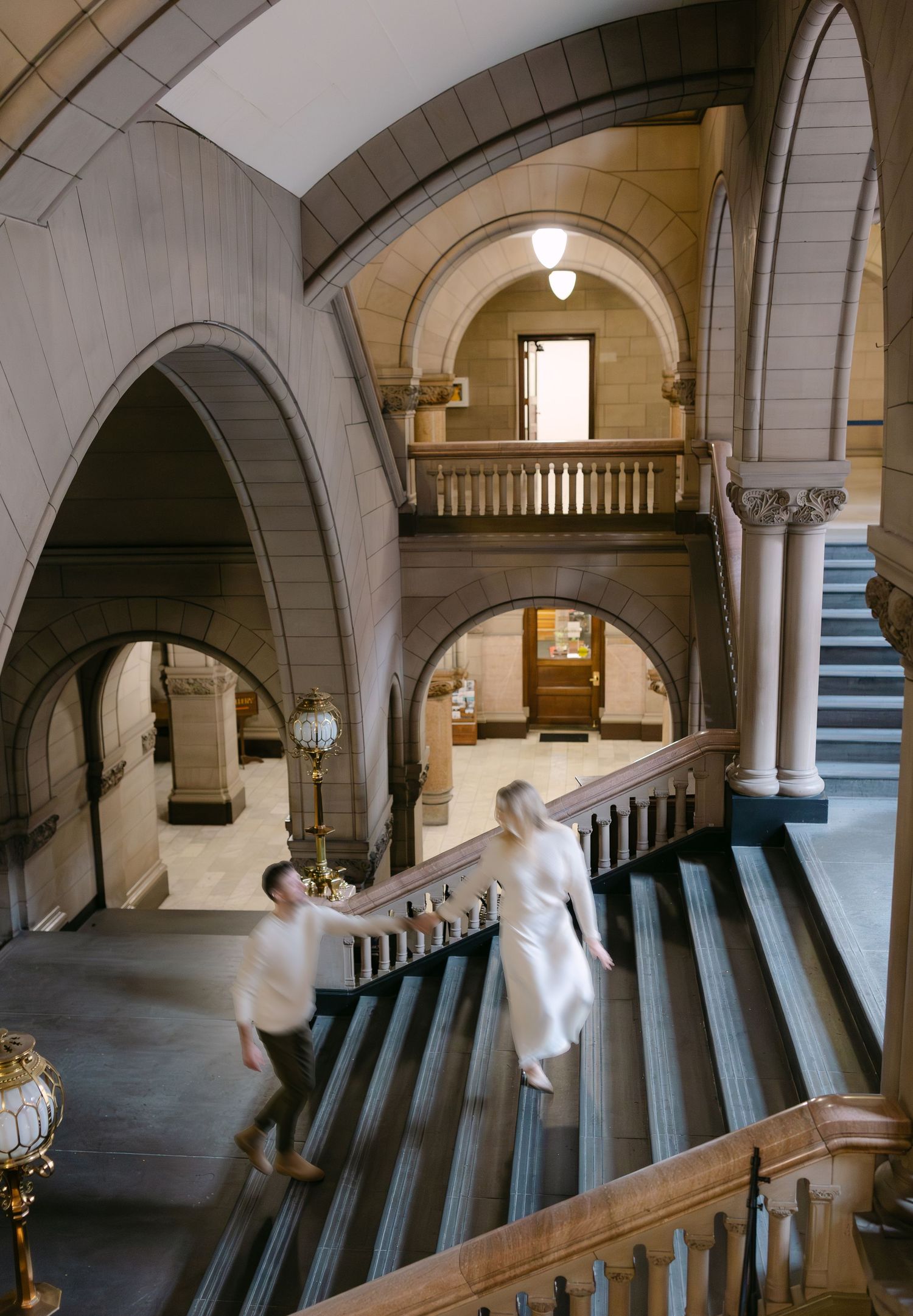 A sequence of photos showing a couple dancing and twirling in an elegant arched hallway with stone columns.