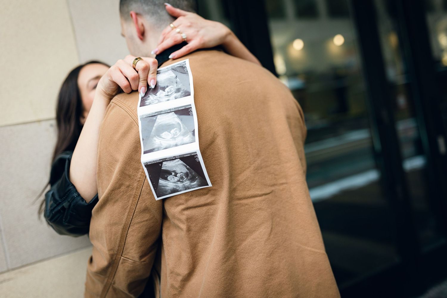 An emotional pregnancy announcement moment captured with an ultrasound photo in outdoor setting.