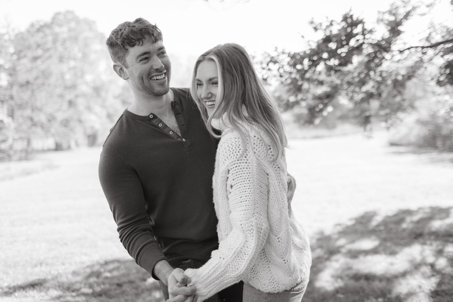 A couple sharing a tender black and white moment outdoors on a sunny day.