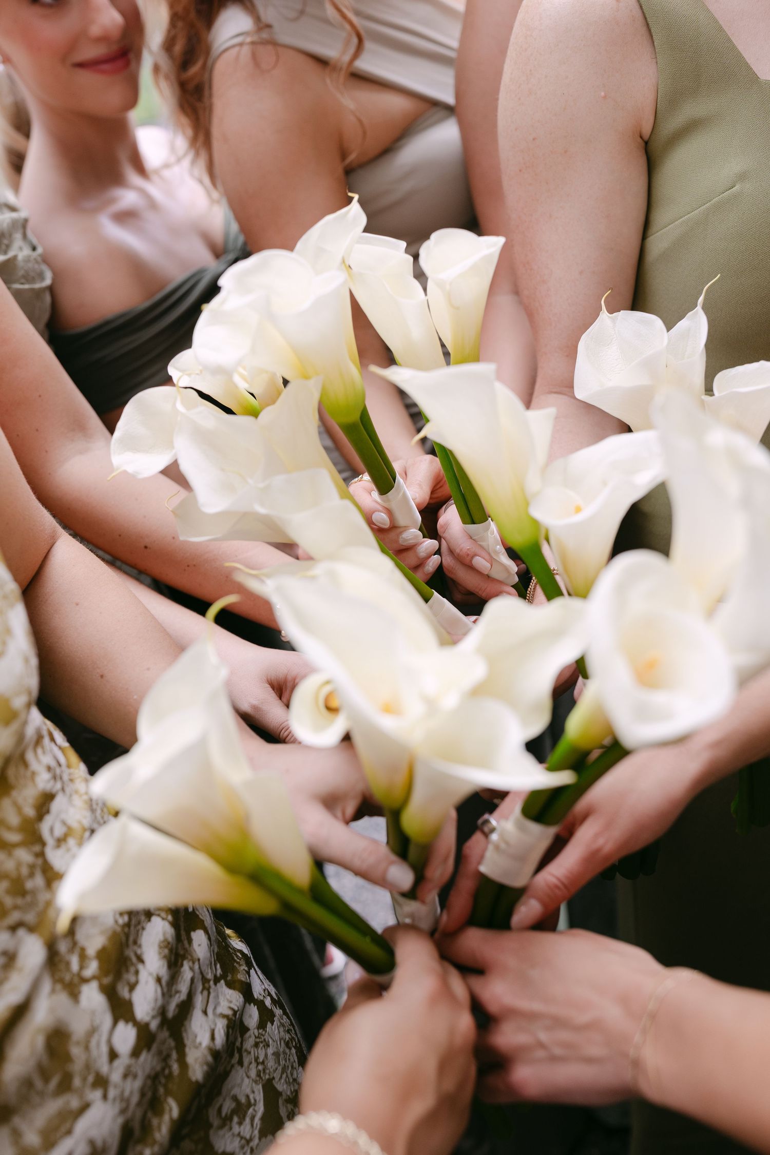 Bridesmaids holding elegant white calla lily bouquets together at a wedding ceremony.